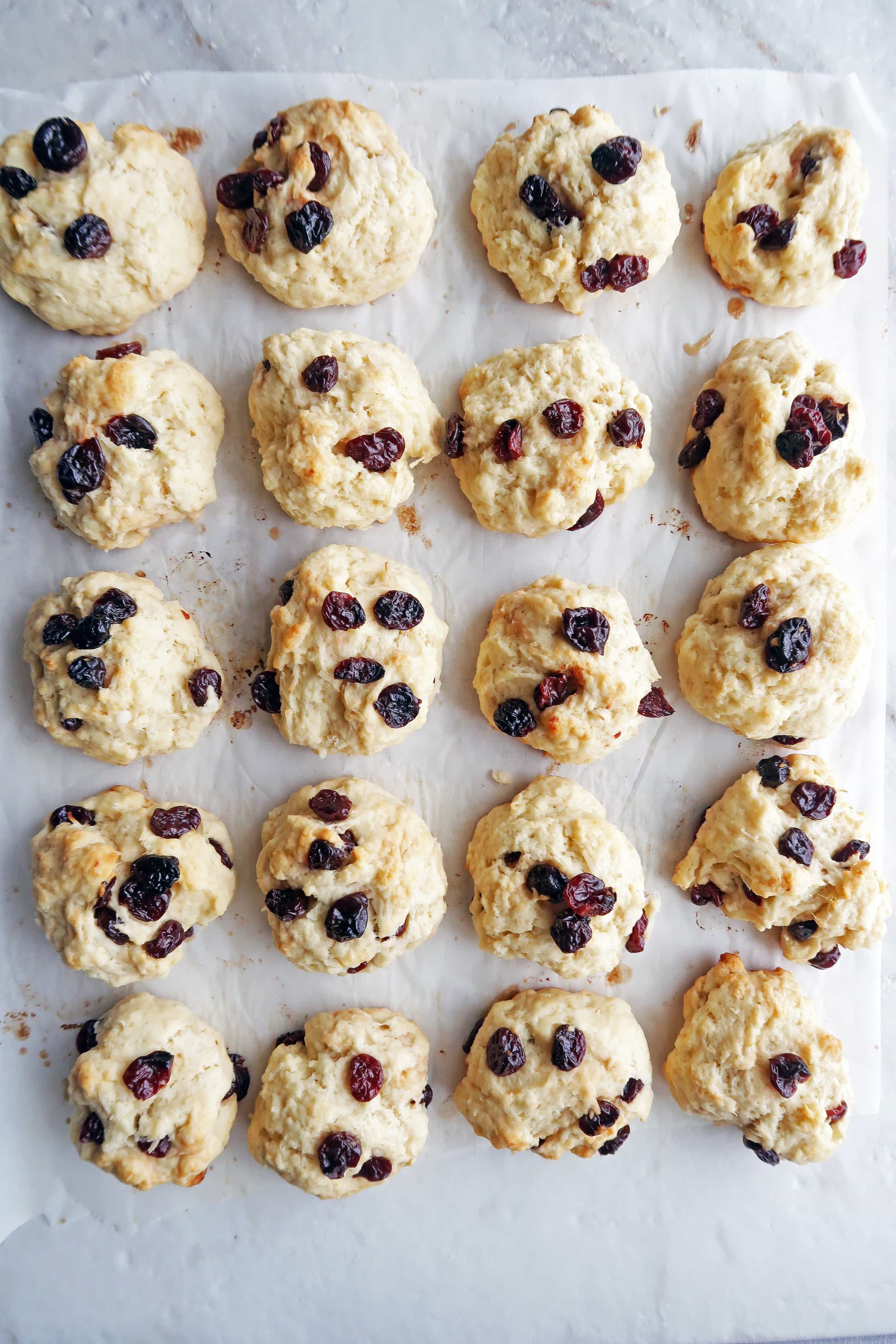 Twenty cherry coconut tea buns lined up in rows of four on parchment paper.