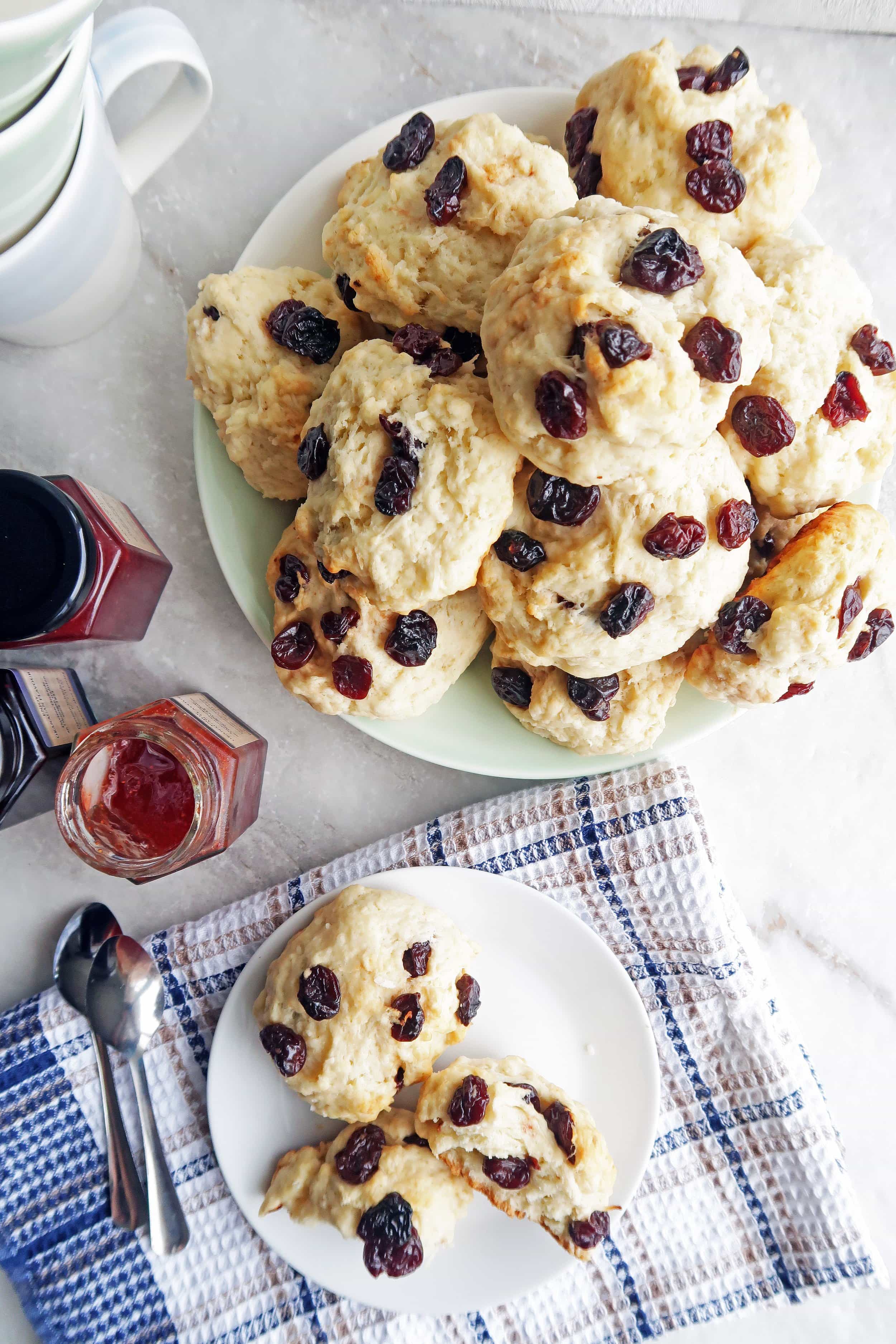 Cherry coconut tea buns piled on a large plate with another small plate of two buns to its side.