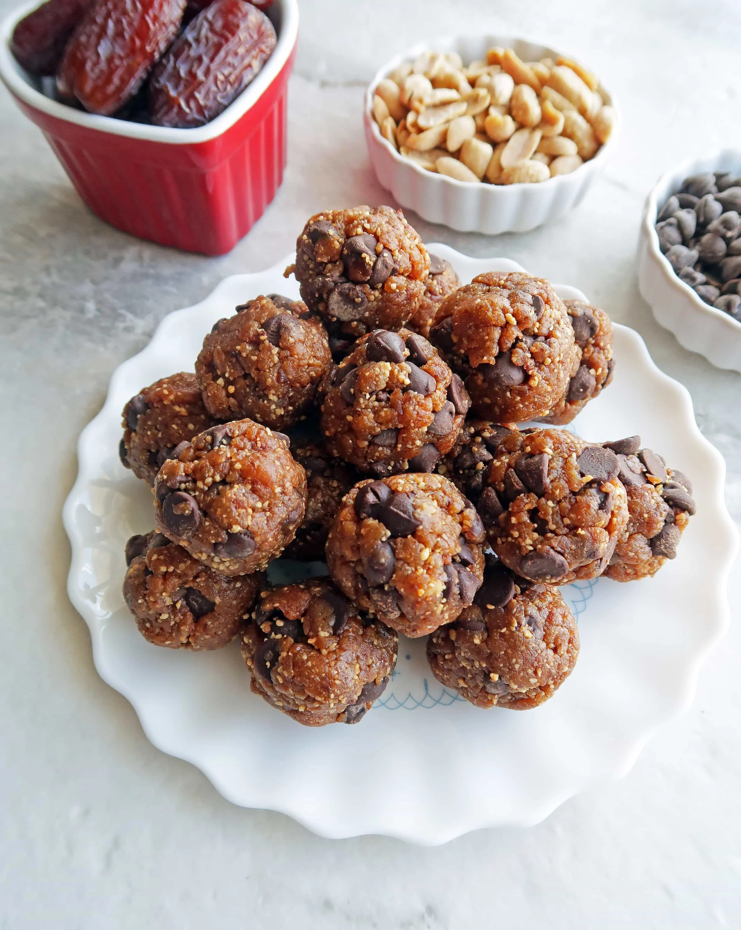 Closeup top angled view of peanut chocolate chip energy balls piled on a white plate.