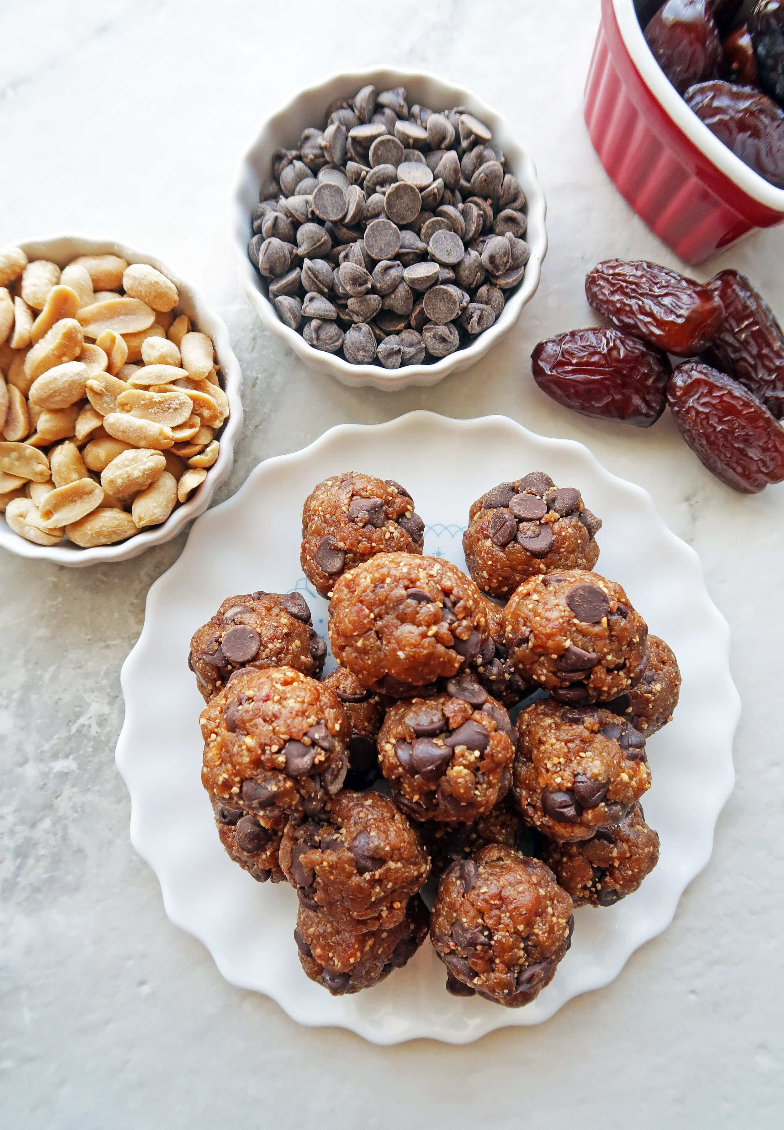 Overhead view of many peanut chocolate chip energy balls piled on a white plate.