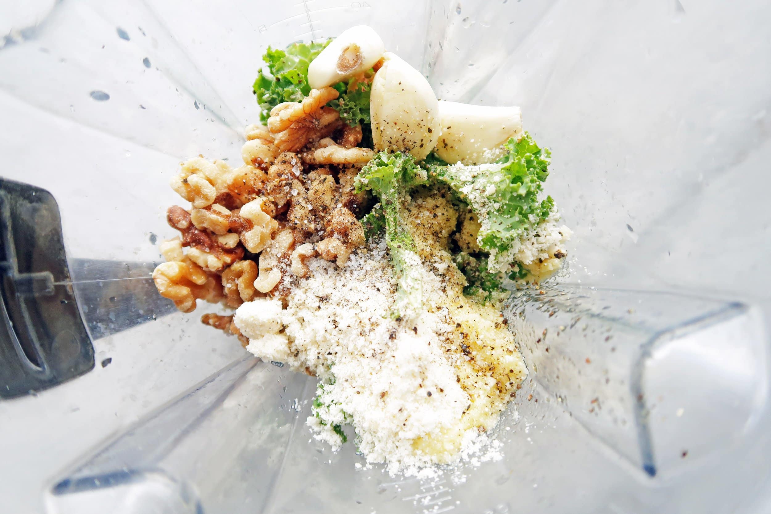 A blender containing kale walnut pesto ingredients.