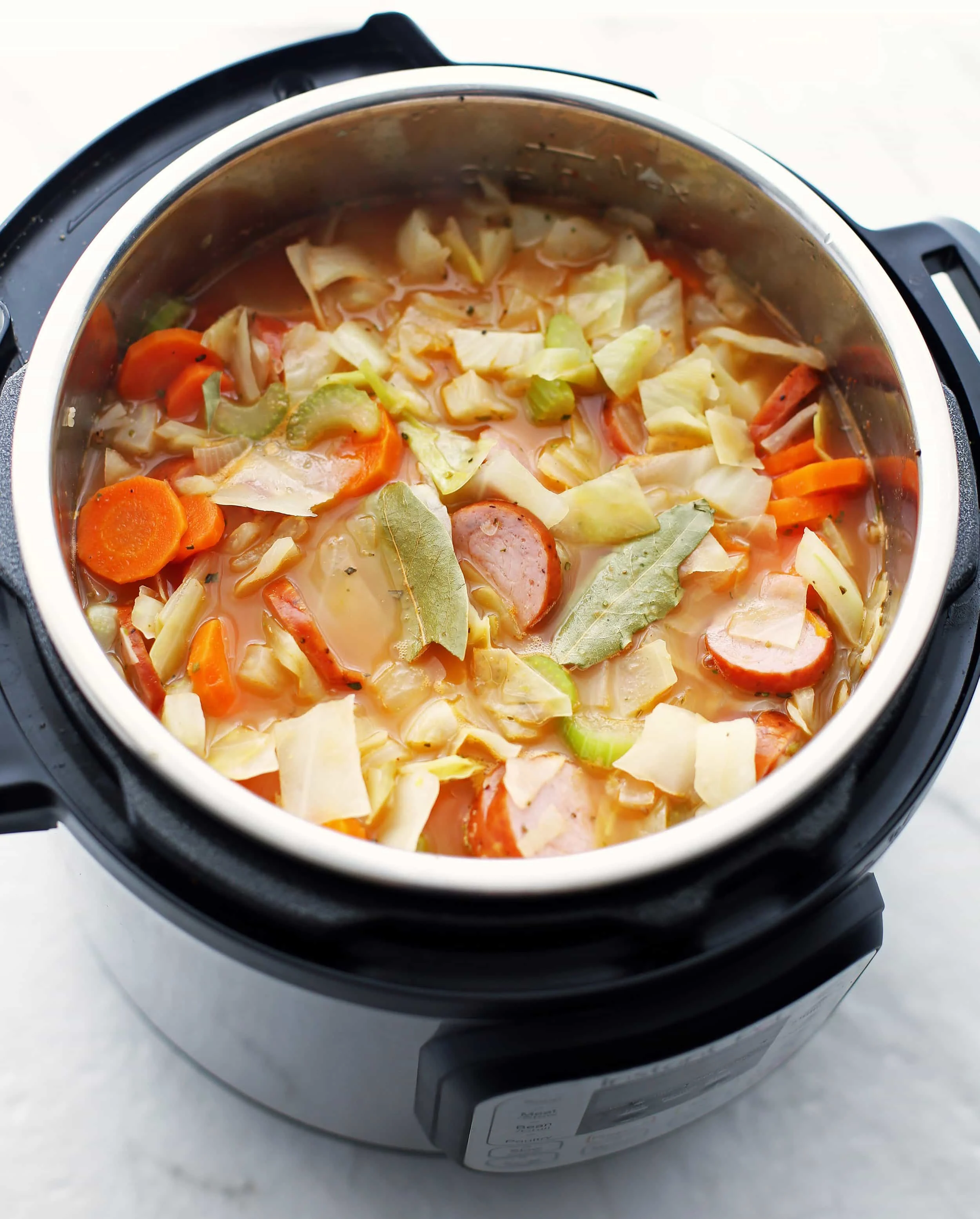 Prepared ingredients for fennel, cabbage, and sausage soup placed in the Instant Pot, which includes carrots, celery, onions.