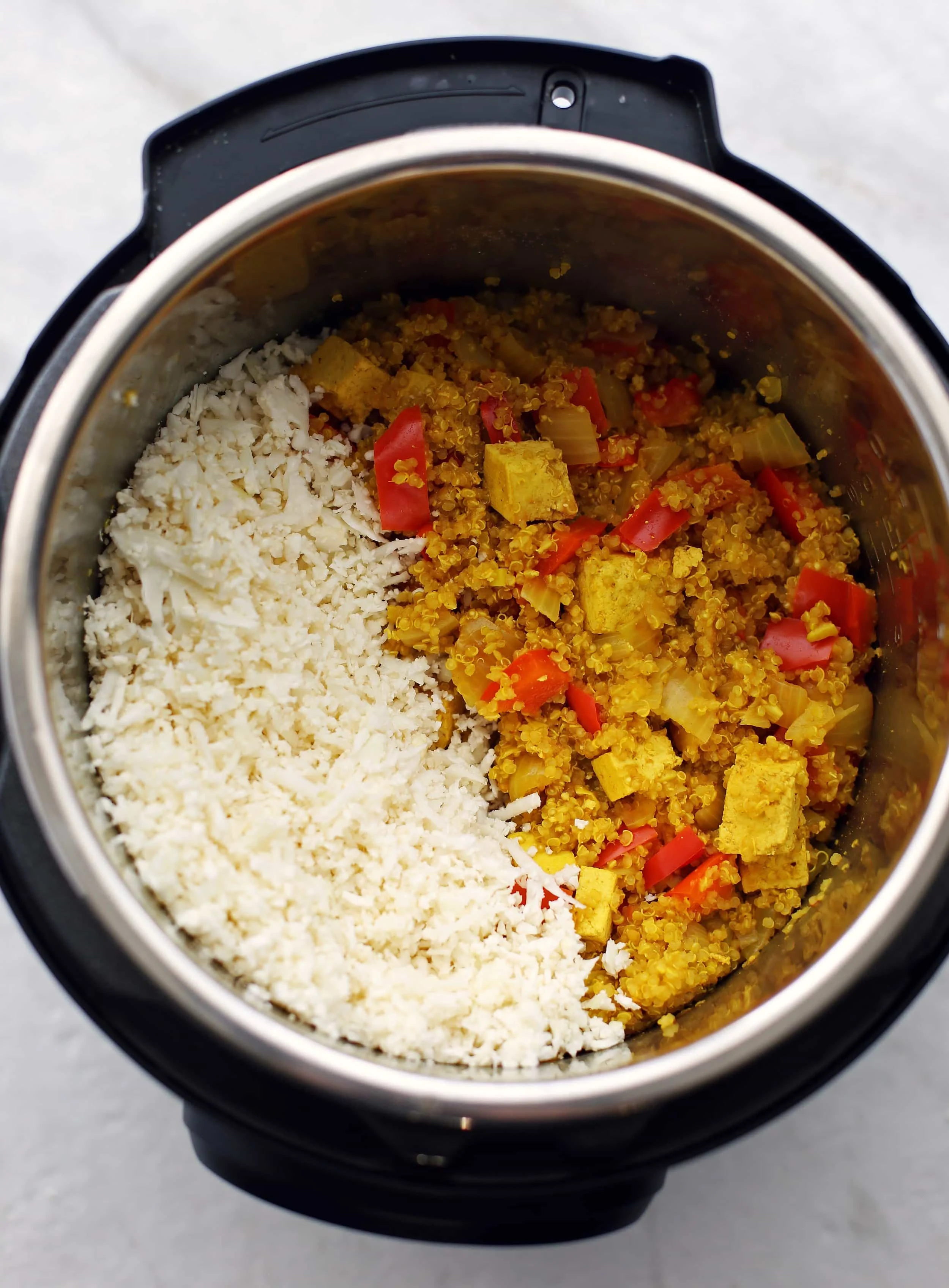 Cooked spiced quinoa, tofu, and bell peppers with cauliflower rice in the Instant Pot.