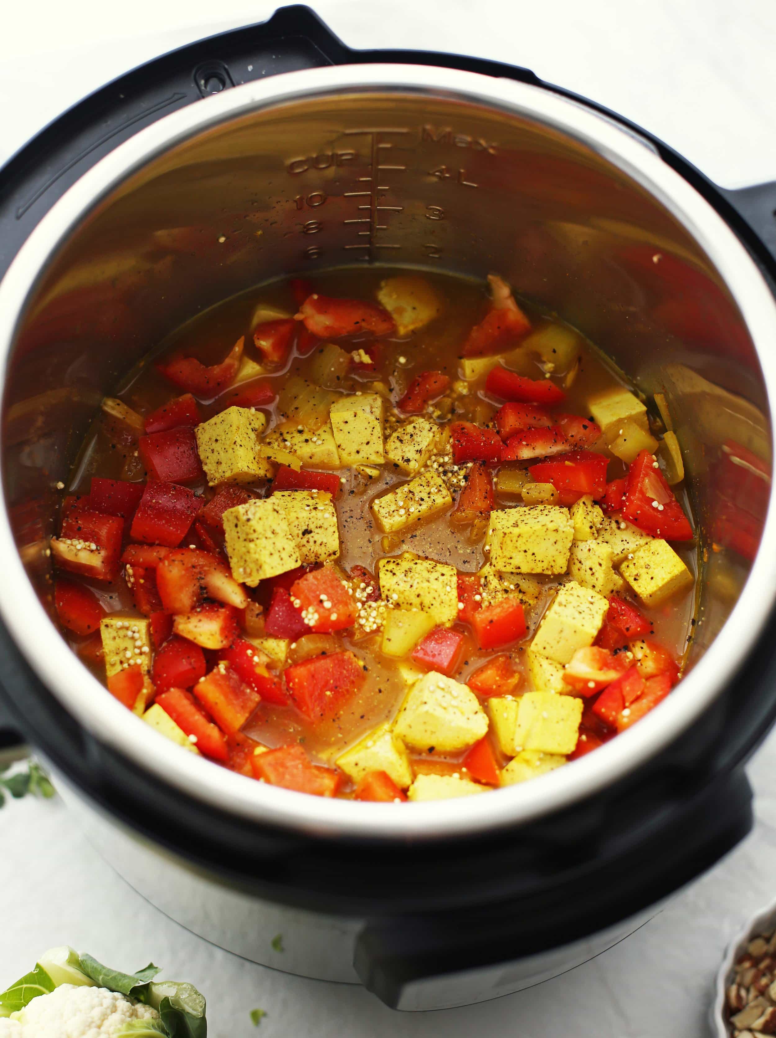 Sautéed onions, garlic, ginger with dry quinoa, tofu, bell peppers, spices, and broth in the Instant Pot.