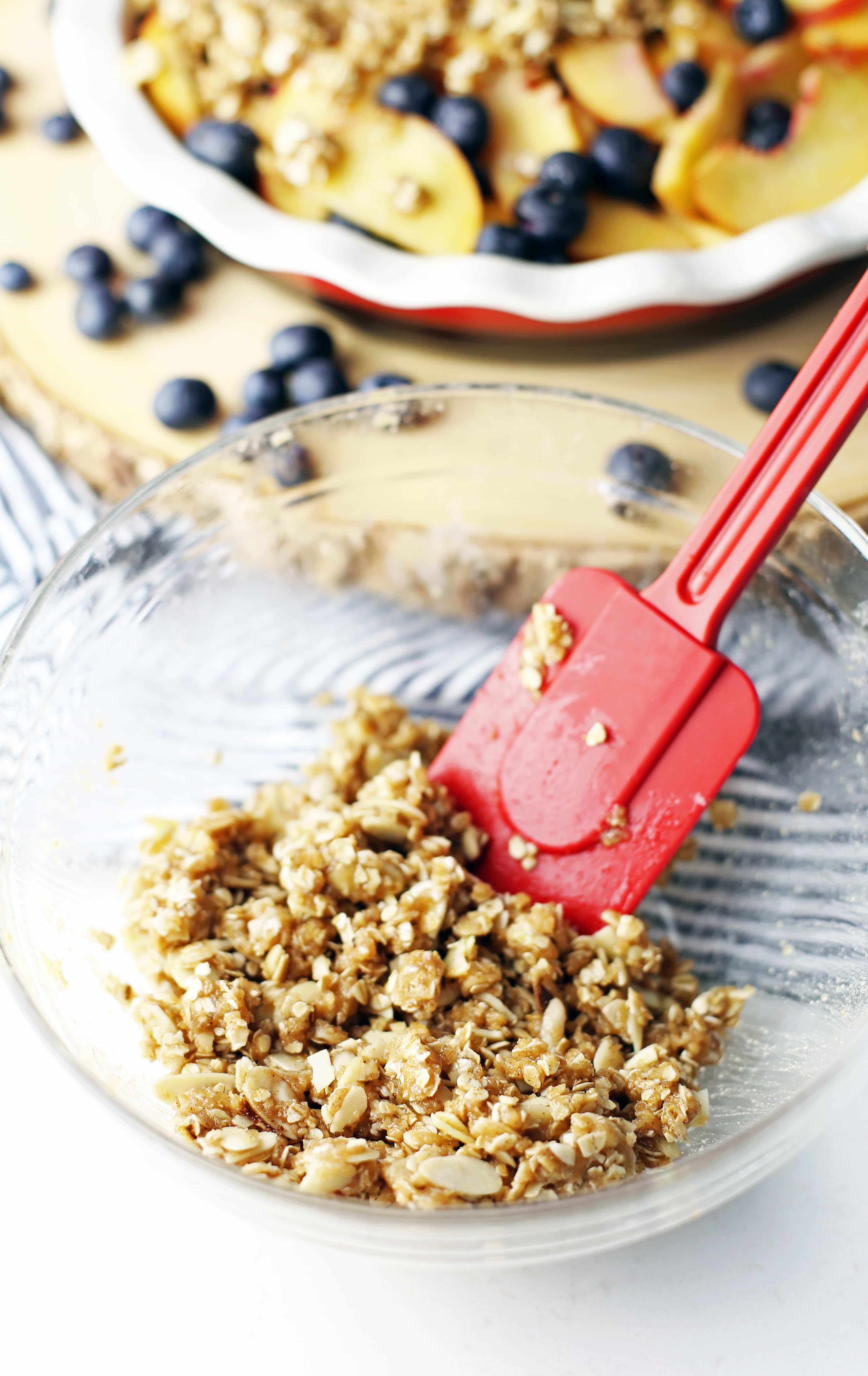 Almond oat topping ingredients combined together in a glass bowl.