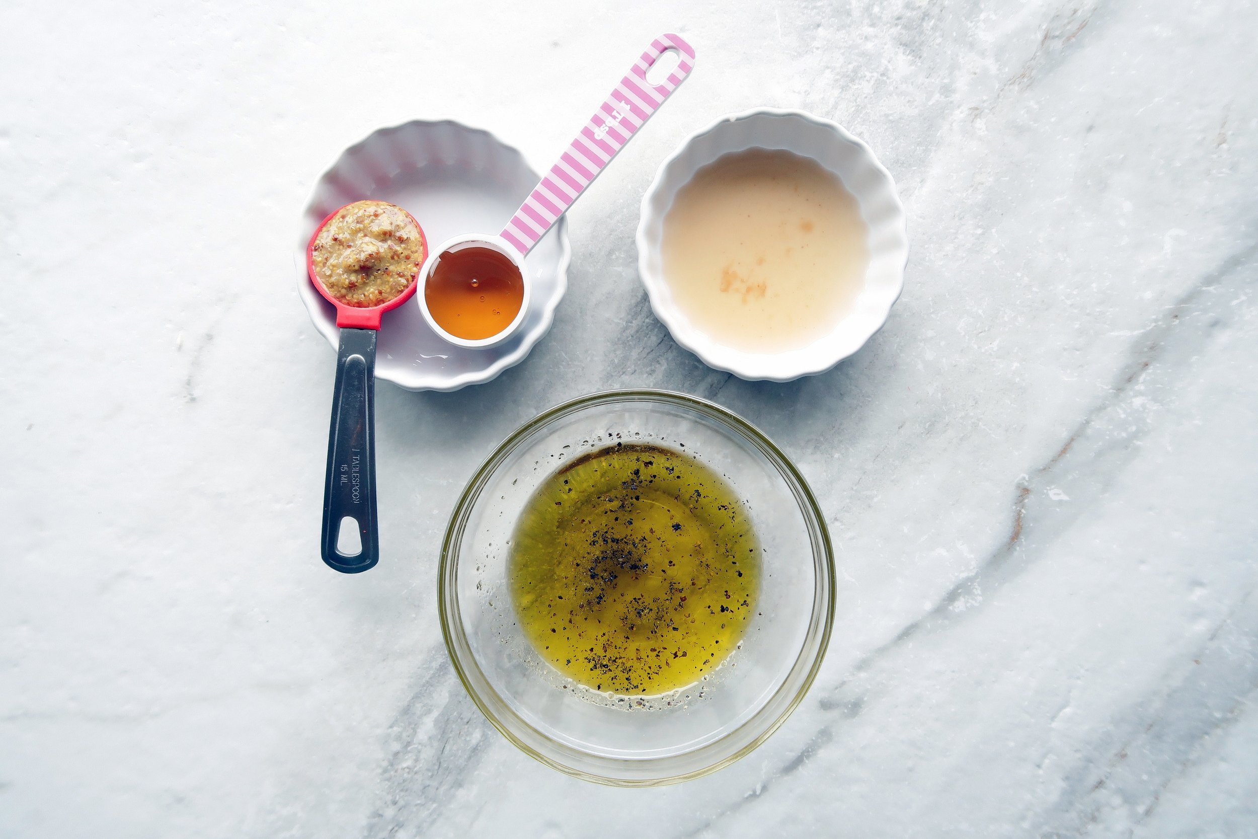 Bowls of olive oil, apple cider vinegar, honey, and dijon mustard.