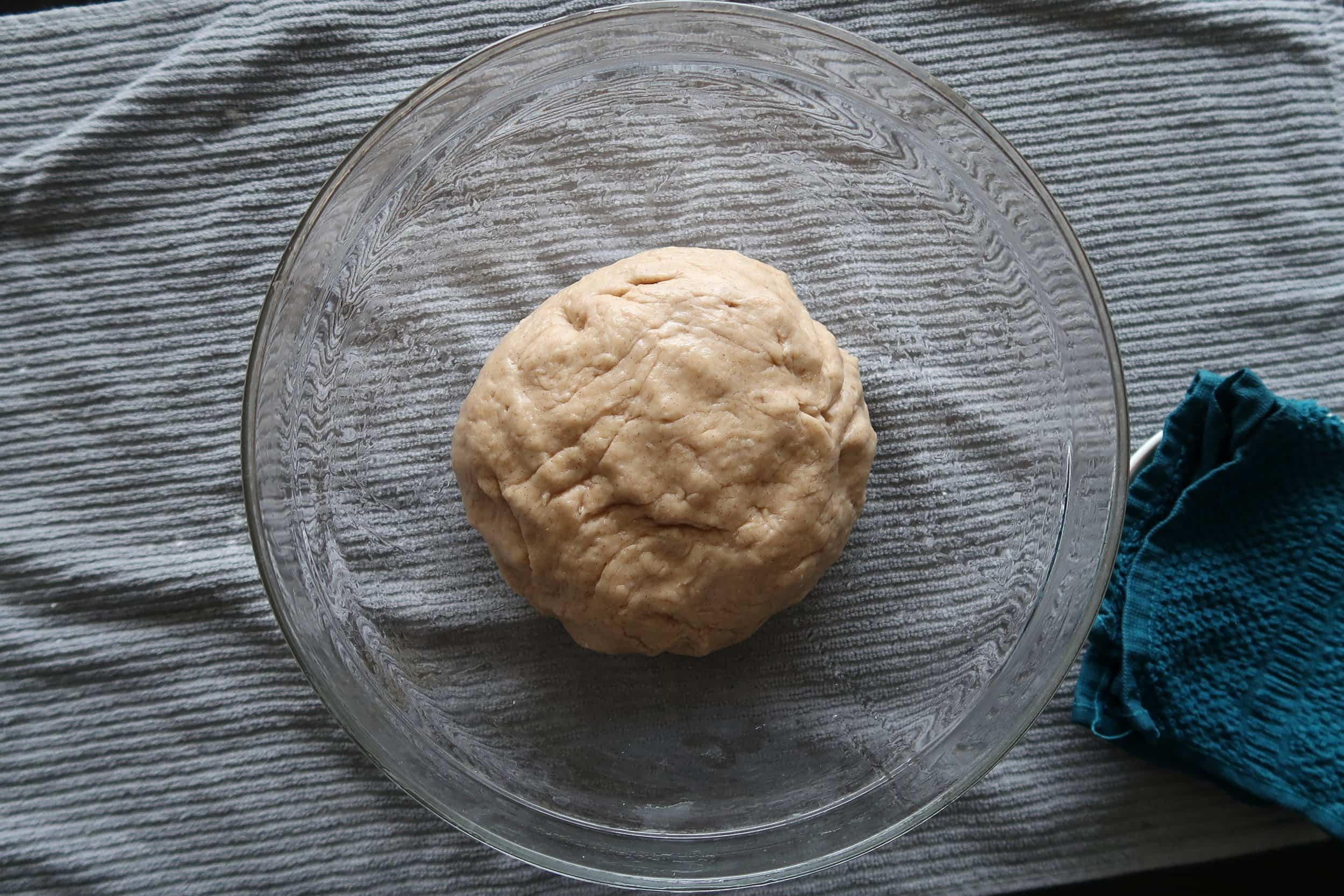 Cinnamon roll dough in a glass mixing bowl.