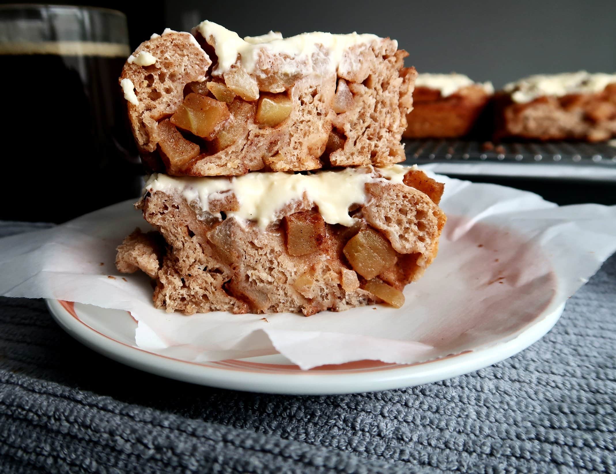 Two halves of an Apple Cinnamon Roll stacked on a plate.