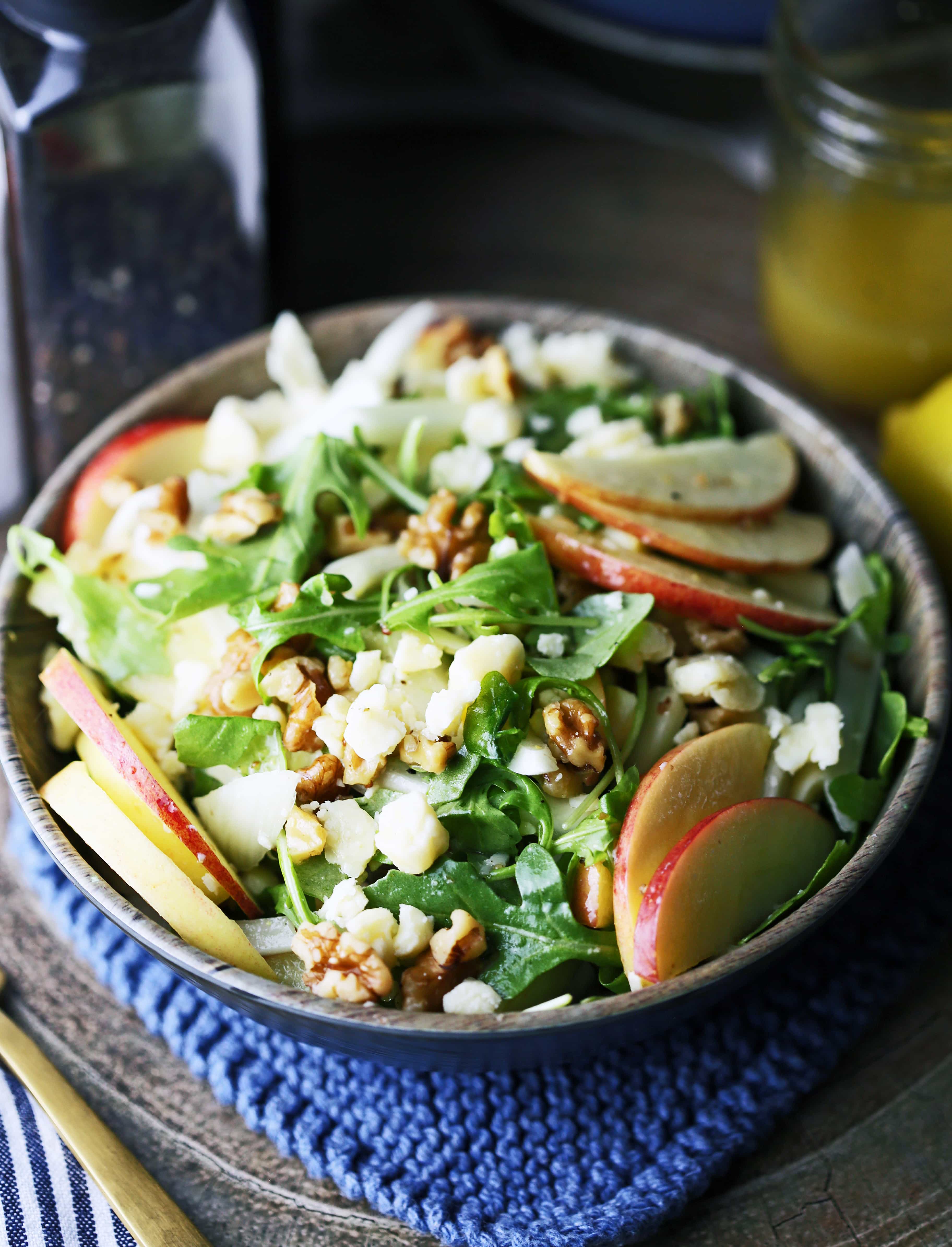 Apple fennel arugula salad with honey lemon dressing in a brown bowl.