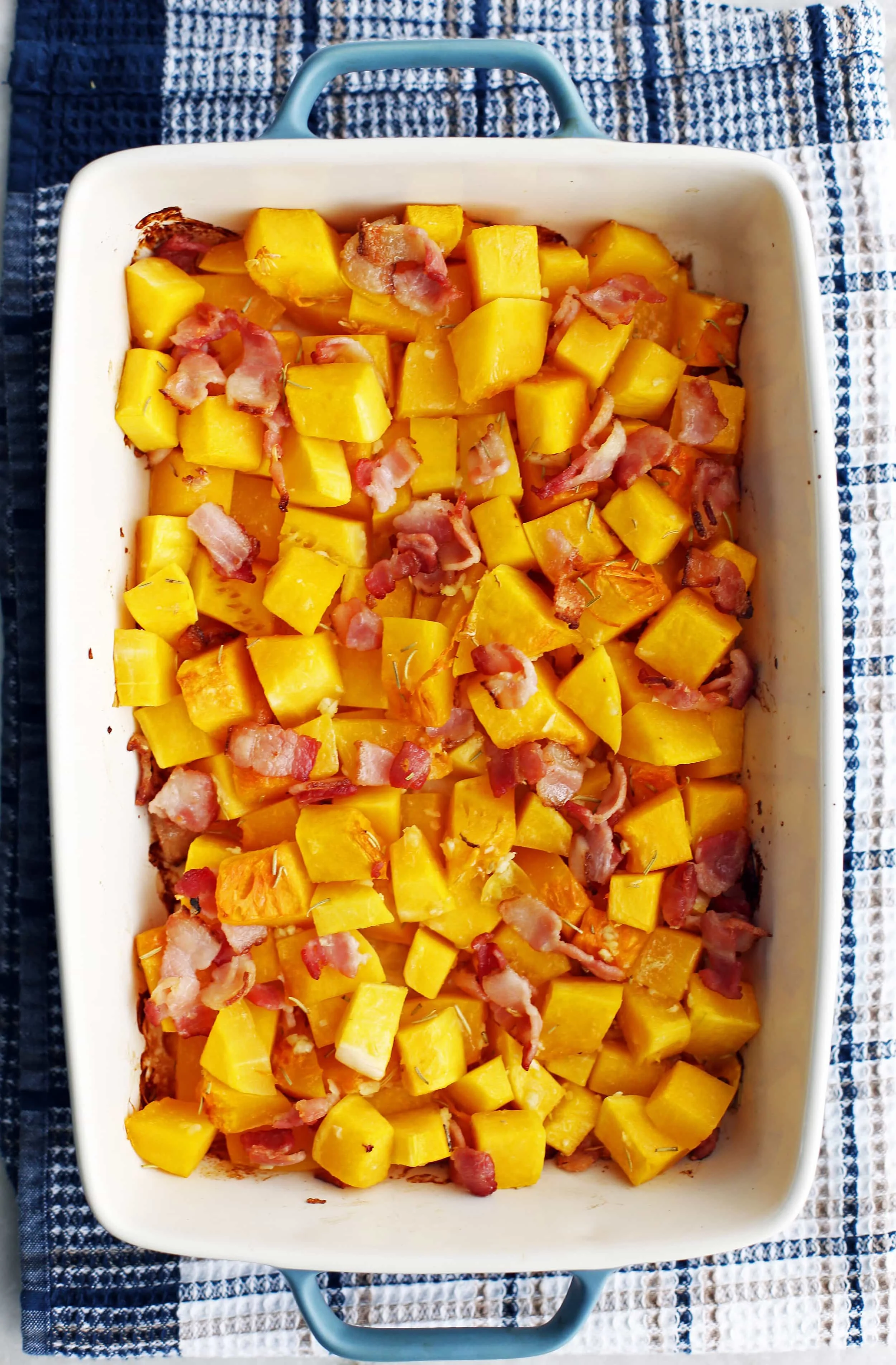 Baked butternut squash and chopped bacon in a large baking dish.