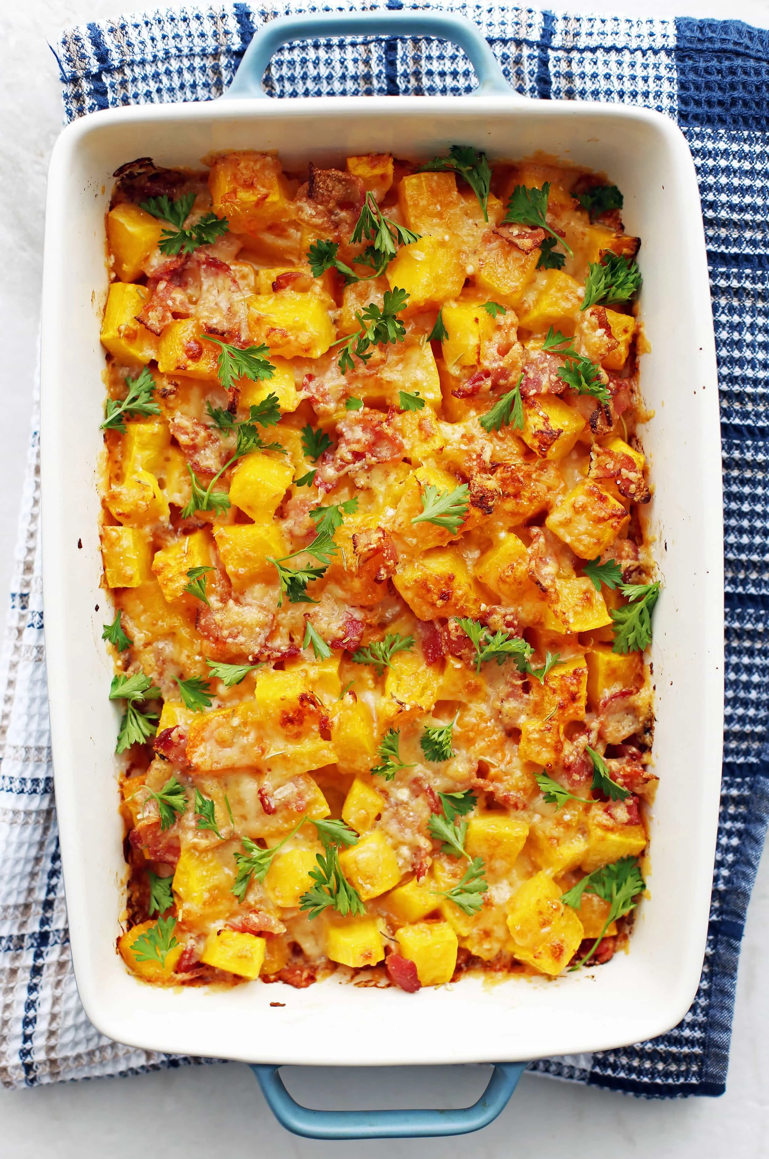 Baked Bacon Cheese Butternut Squash garnished with parsley in a large baking dish.