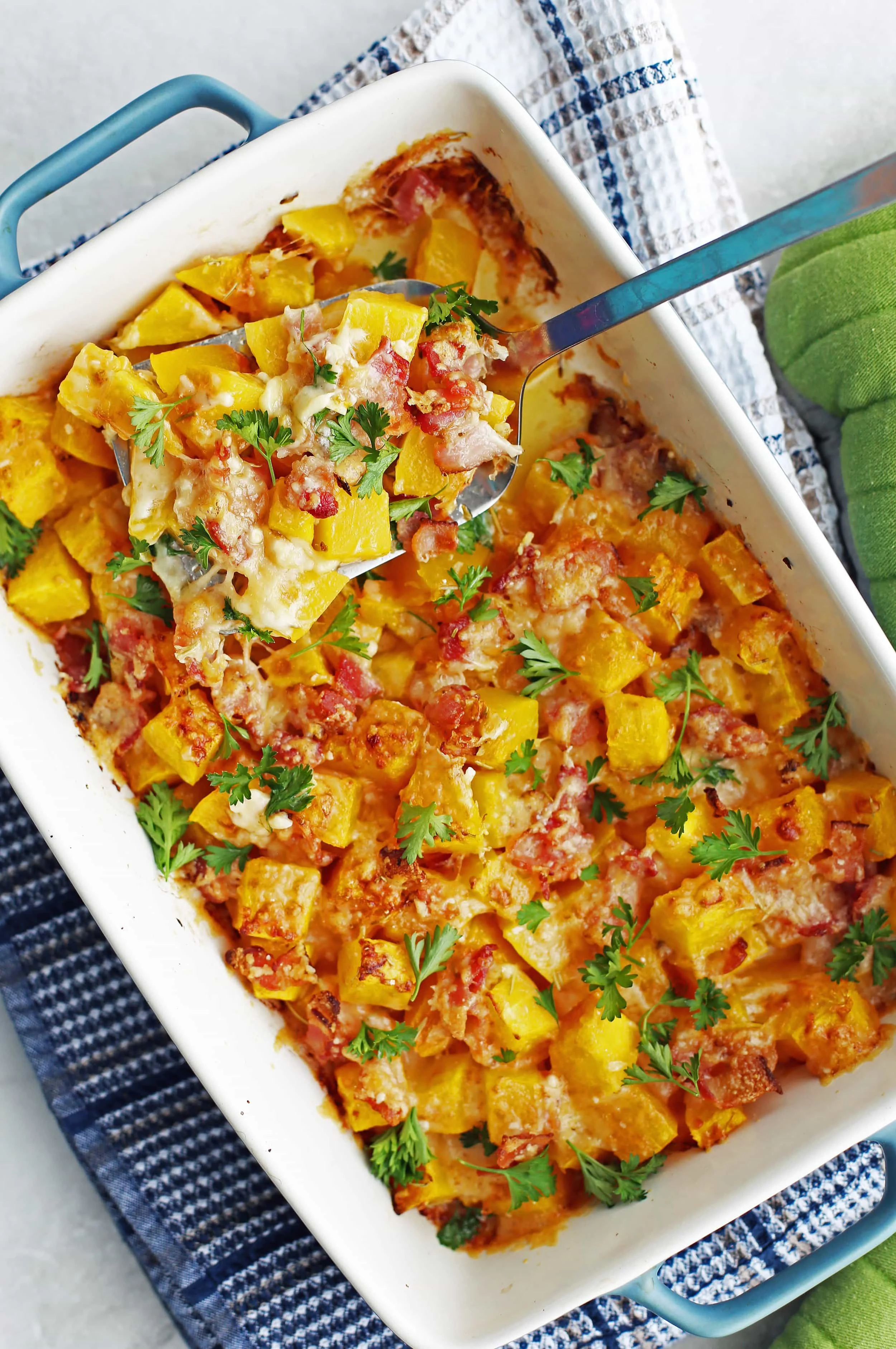 Baked Bacon Cheese Butternut Squash with parsley on top in a blue baking dish.