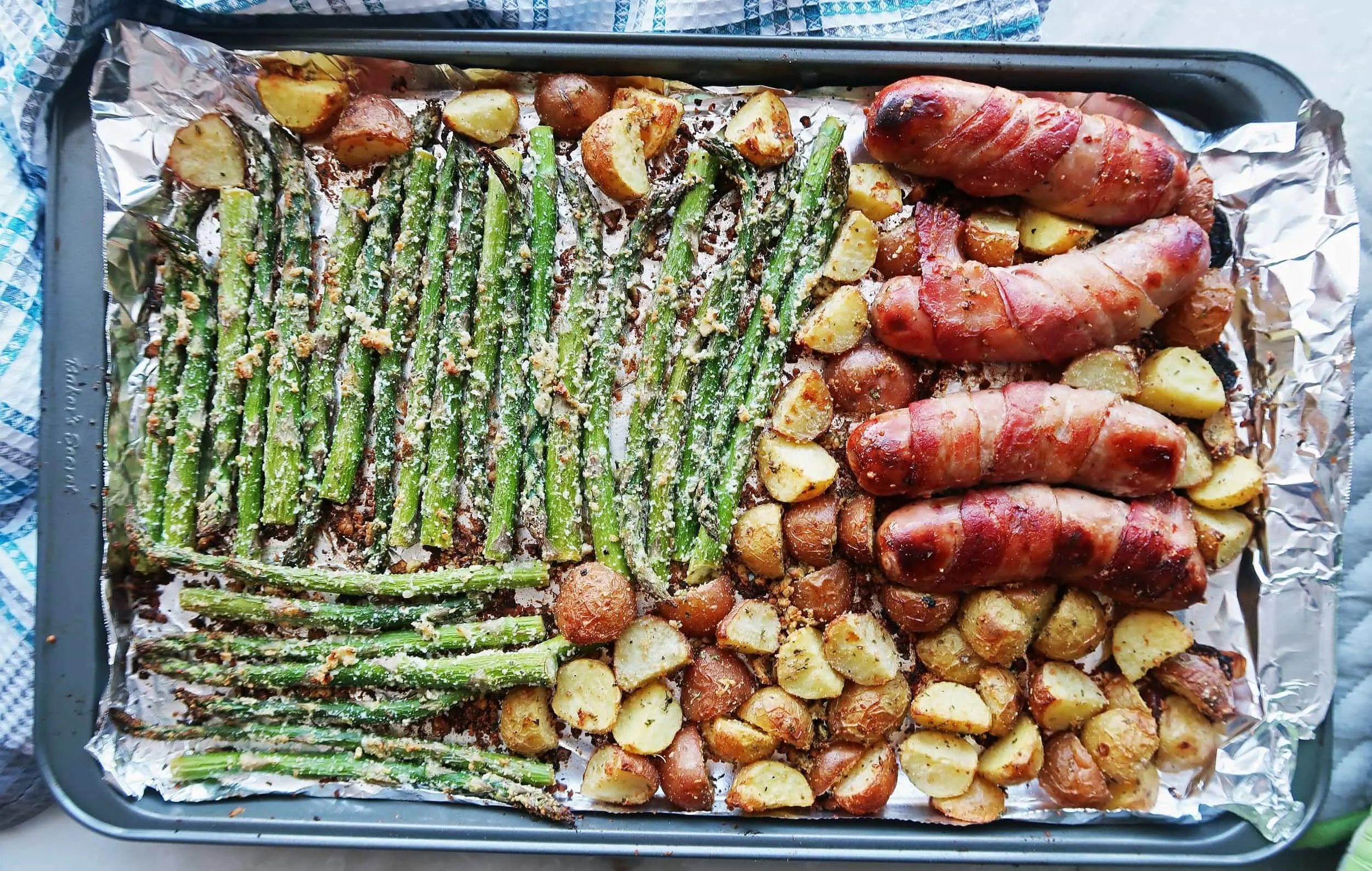 A sheet pan meal featuring roasted sausages, potatoes, and asparagus.