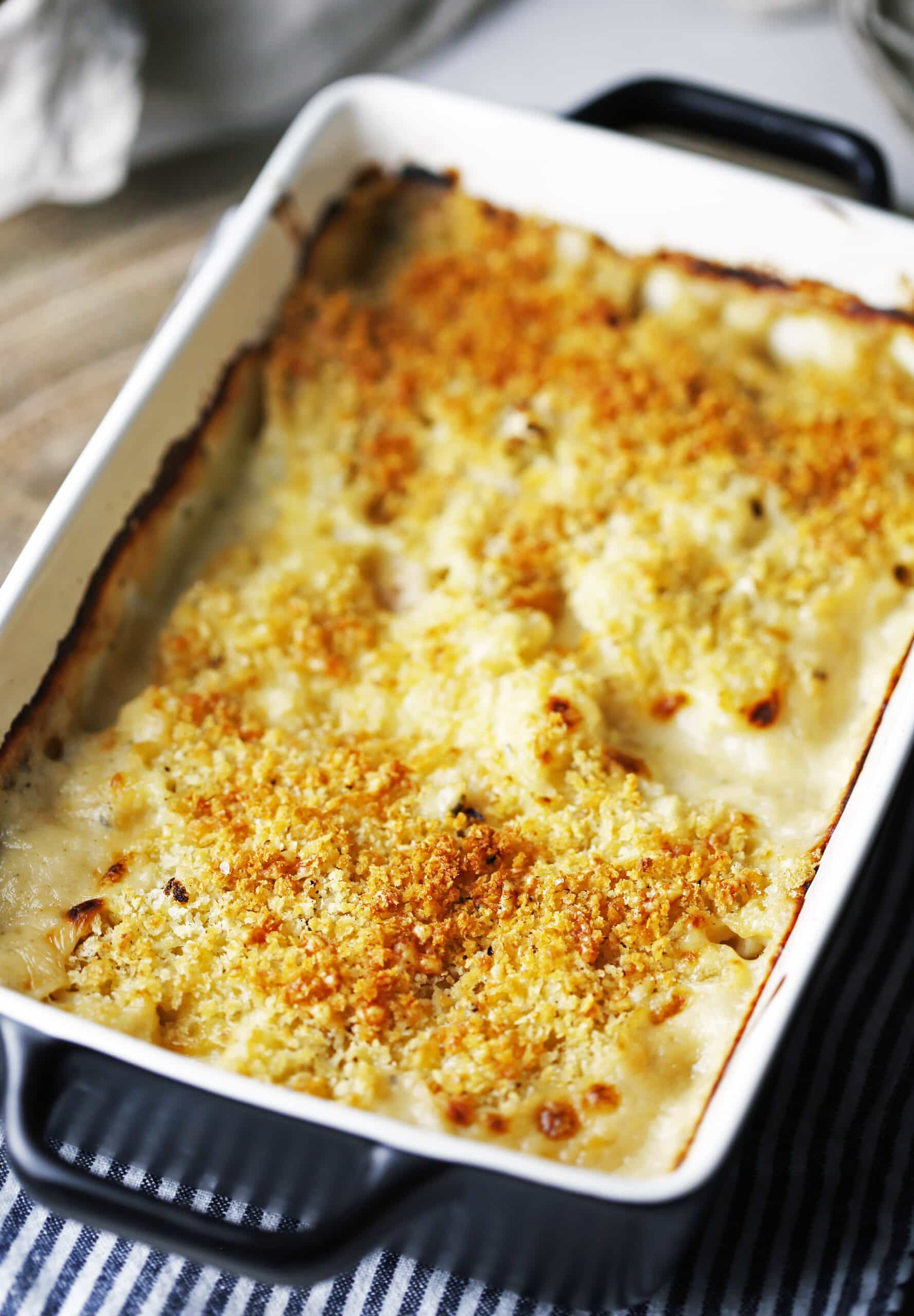 Baked cauliflower gratin with a crunchy panko topping in a black casserole dish.