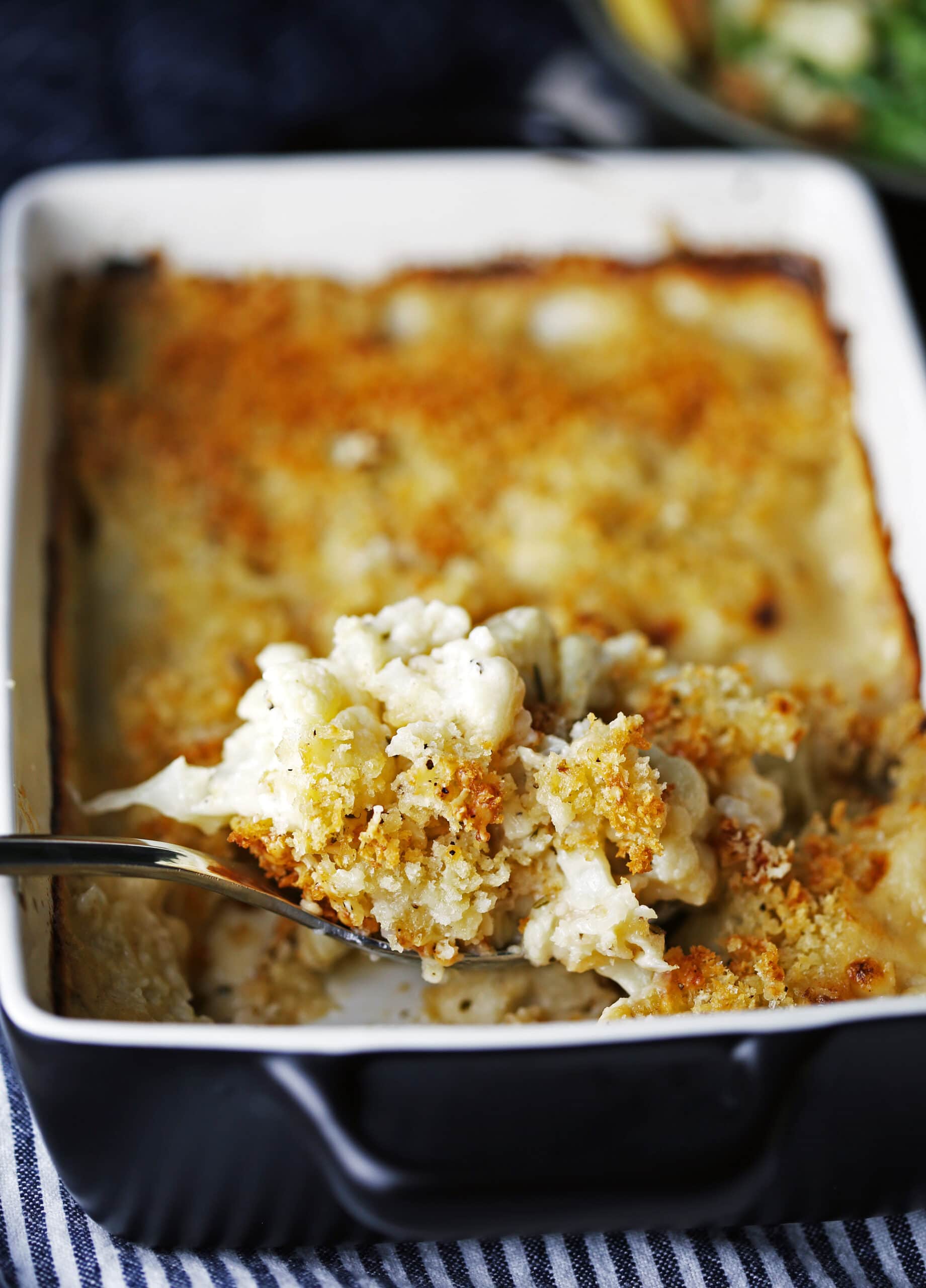 A scoop of cauliflower gratin taken out of the casserole dish.