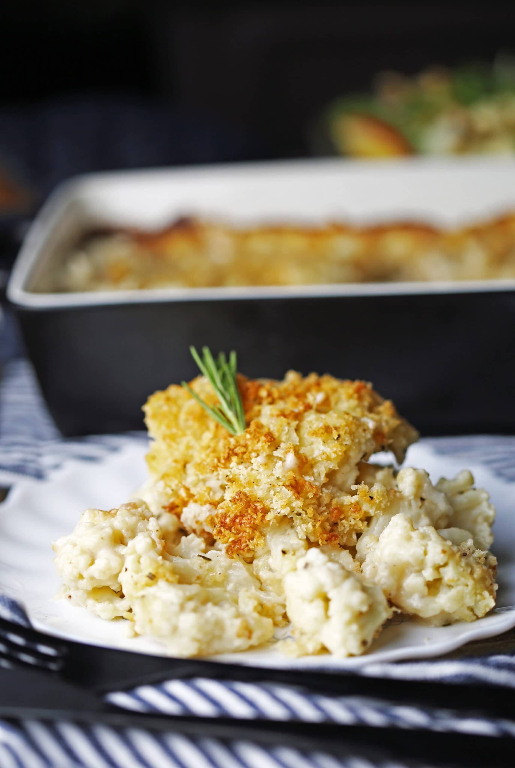 A side view of a hearty scoop of cauliflower gratin on a white plate.