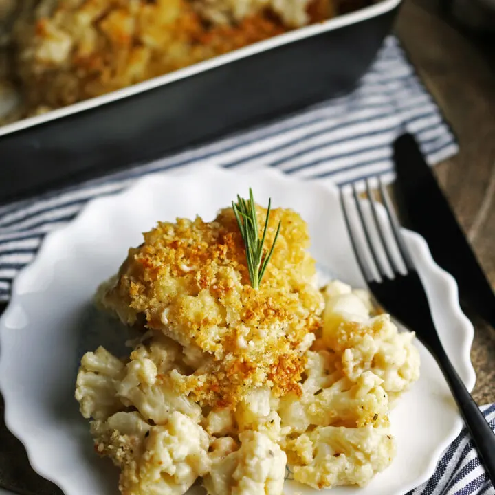Baked cauliflower gratin topped with crunchy breadcrumbs on a white plate.