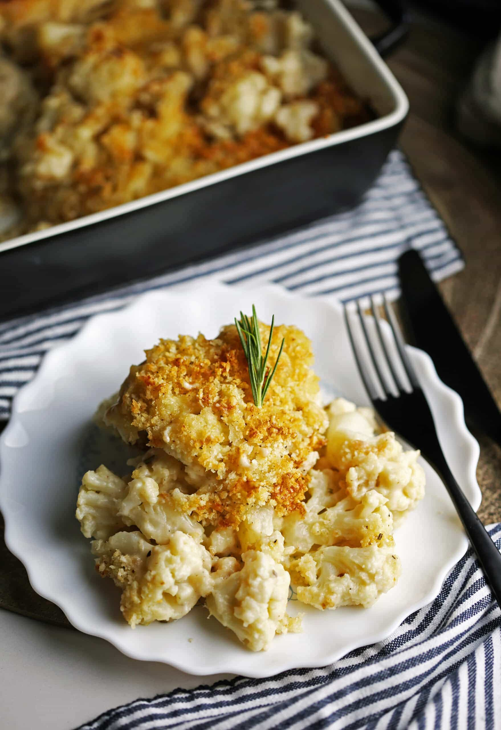 Baked cauliflower gratin topped with crunchy breadcrumbs on a white plate.