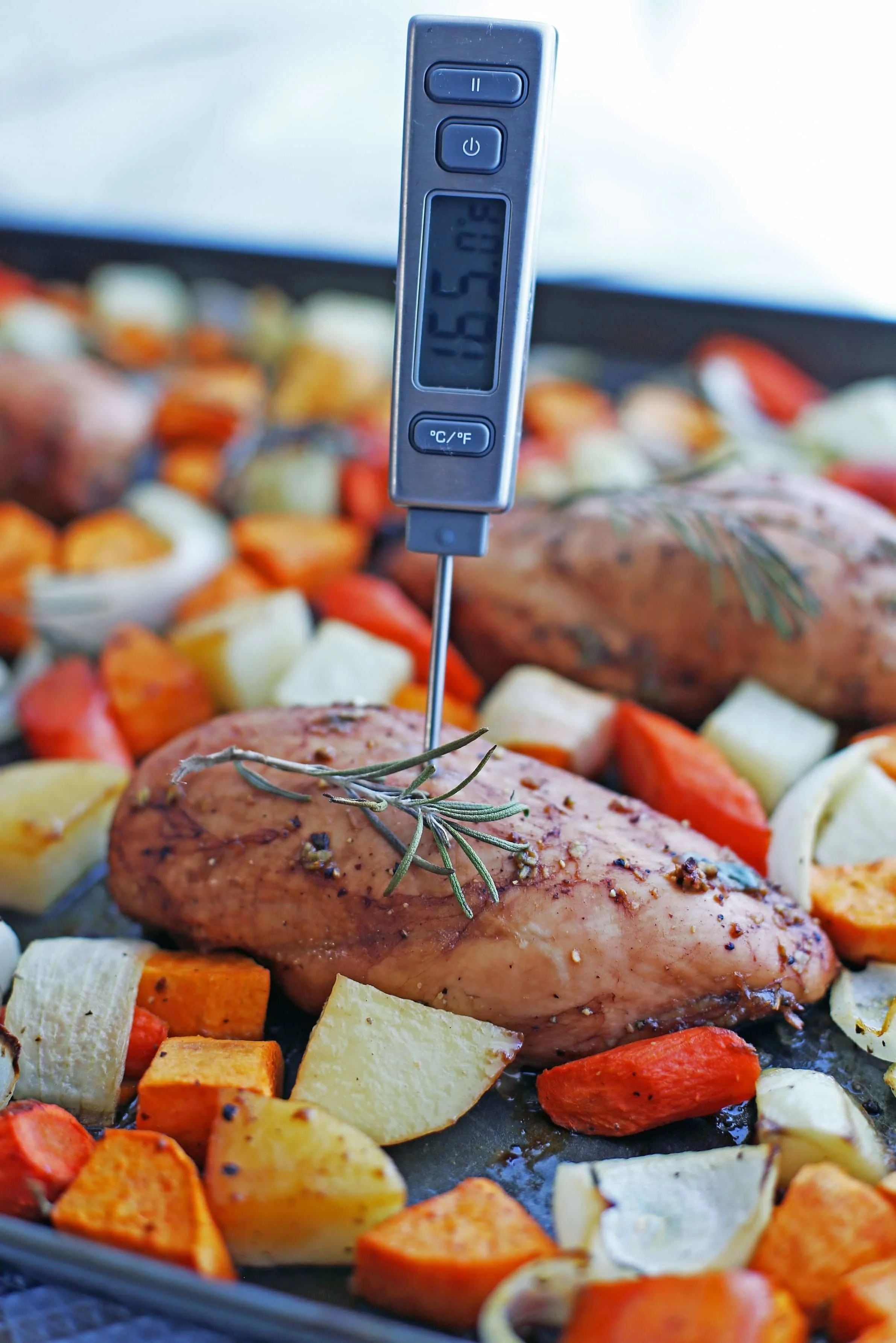 A digital instant read thermometer inserted into a baked balsamic chicken breast that reads “165 degrees Fahrenheit.”