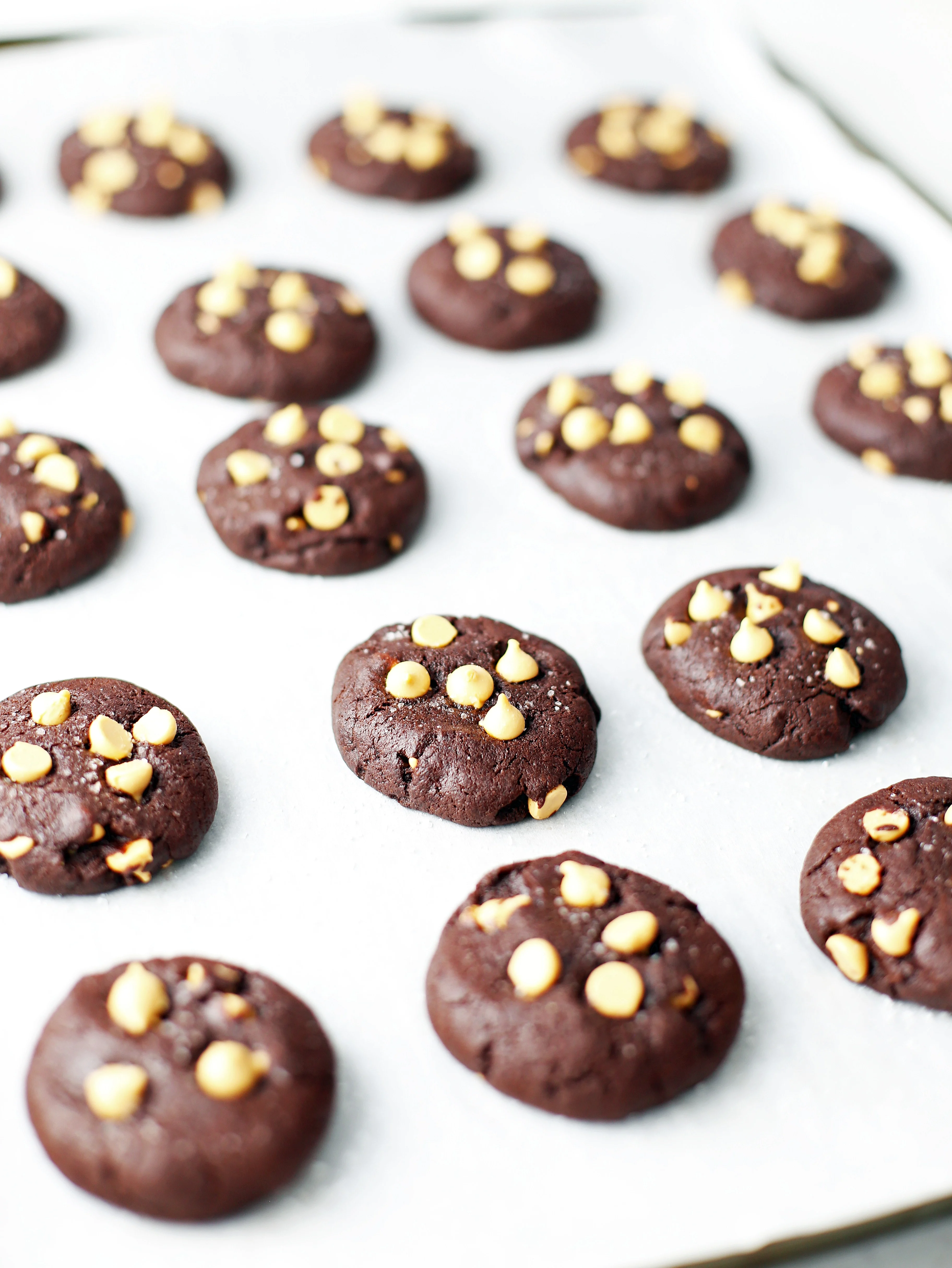 Baked salted chocolate butterscotch cookies on a parchment lined baking sheet.