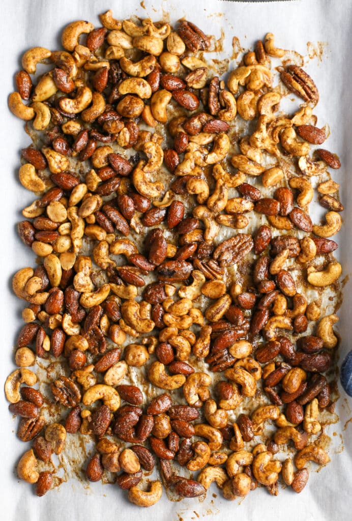 Baked cinnamon sugar mixed nuts spread in a single layer in a large baking sheet.