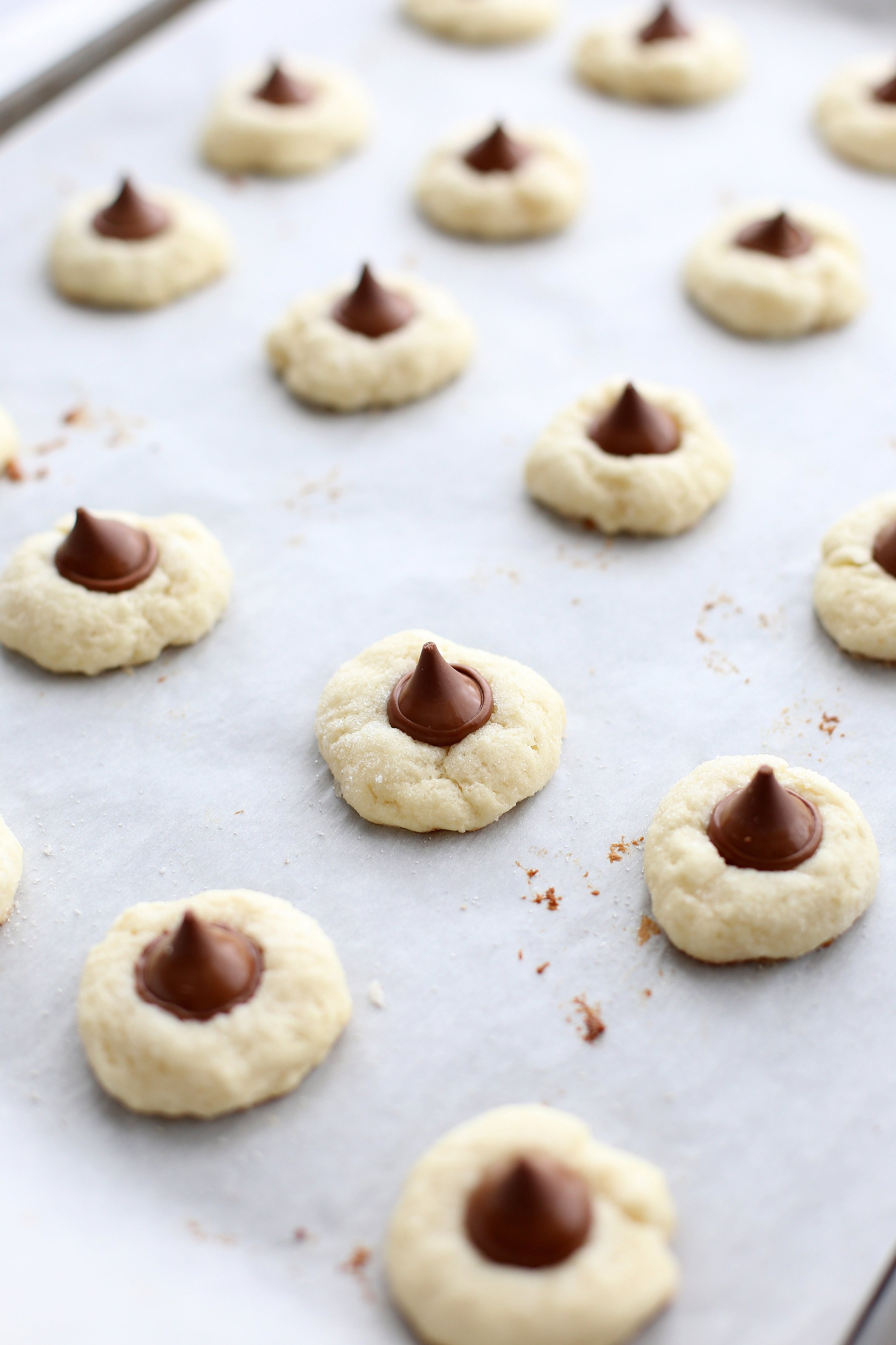 Baked Cream Cheese Kiss Cookies lined up on a parchment paper-lined baking sheet.