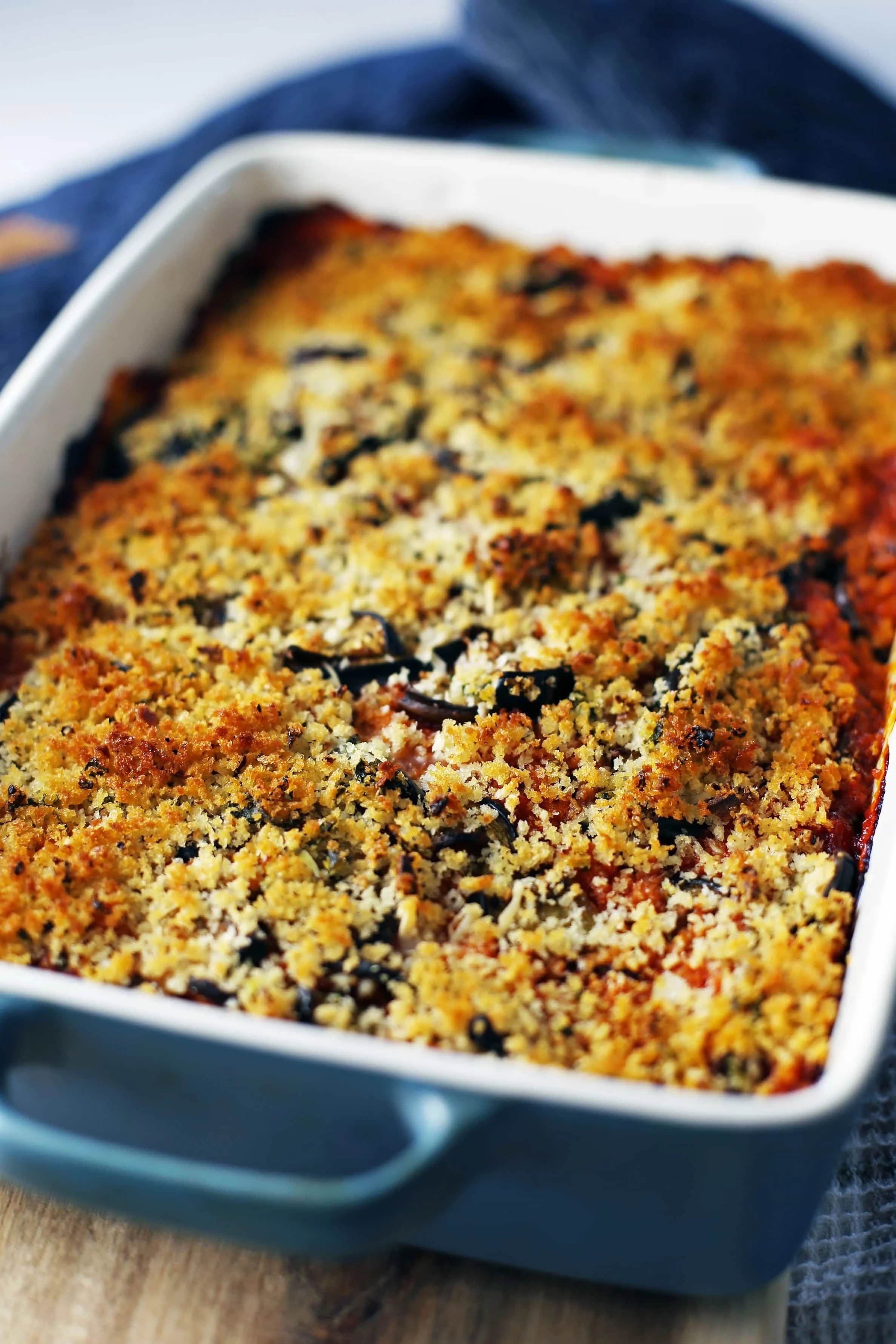 Baked Eggplant Parmesan Casserole with a golden-brown Panko breadcrumb topping in a large blue rectangular dish.