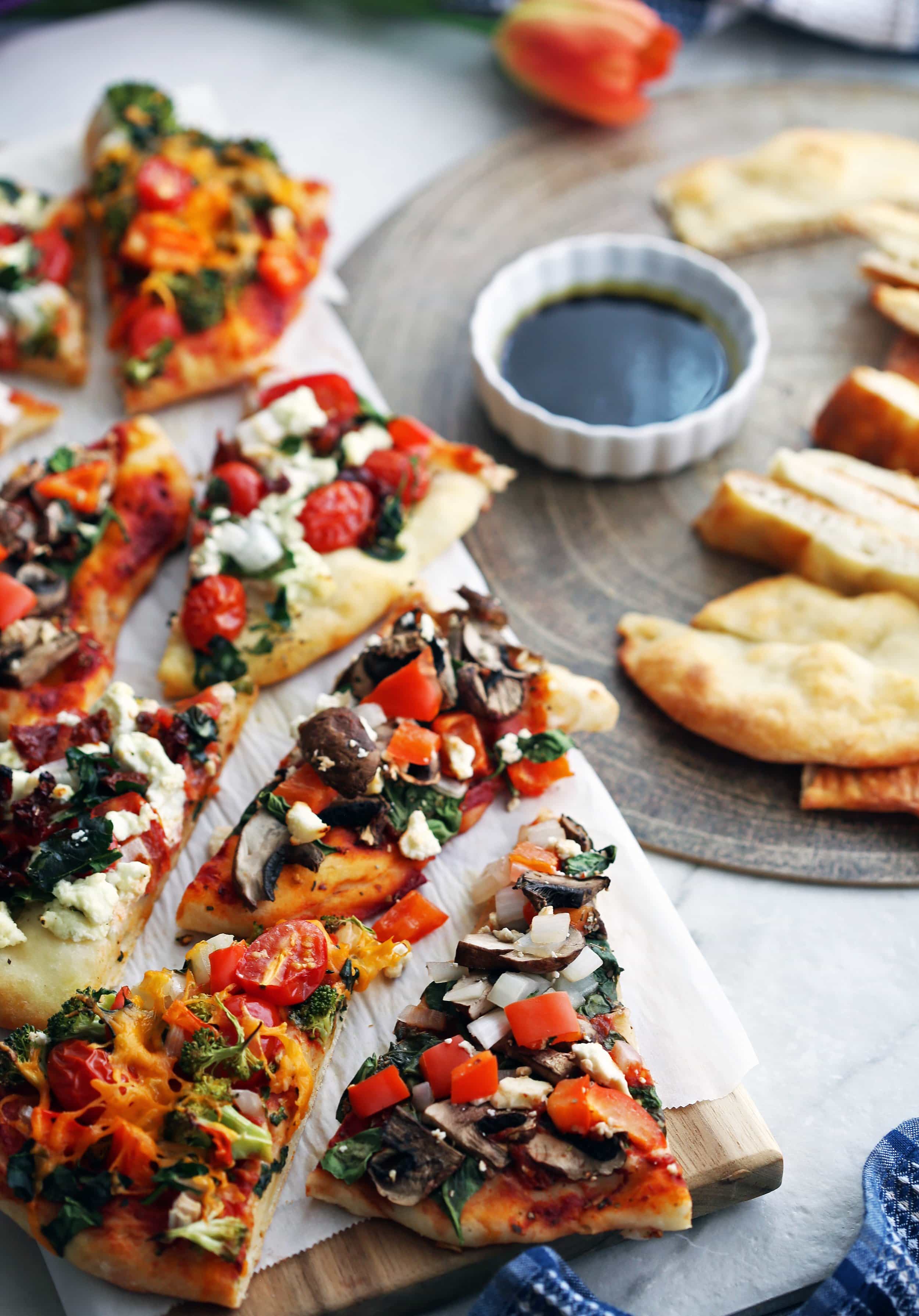 Two platters containing flatbread pizza with various toppings and plain flatbread sliced into pieces.