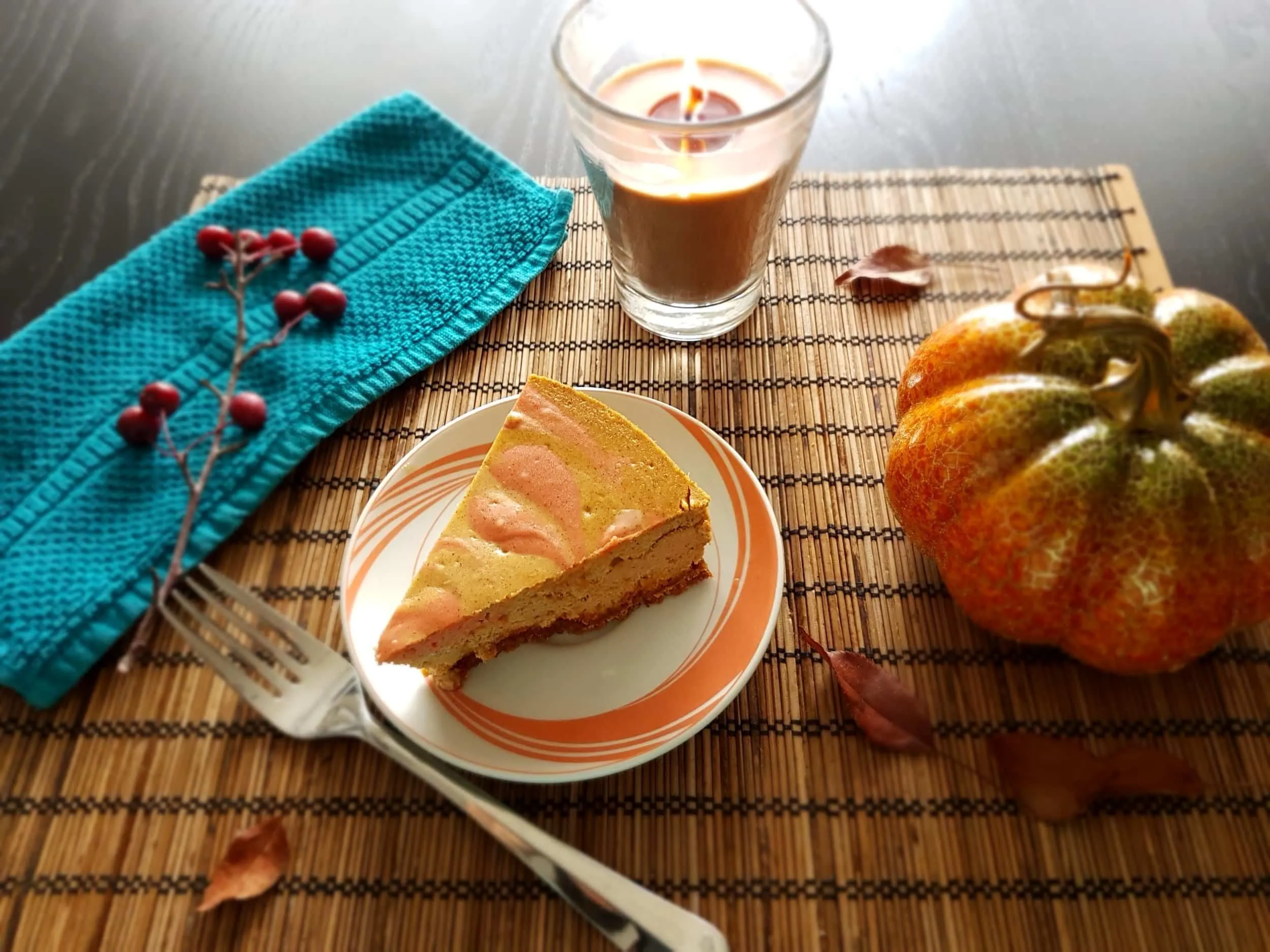 A slice of Baked Pumpkin Cheesecake surrounded by autumn decor.