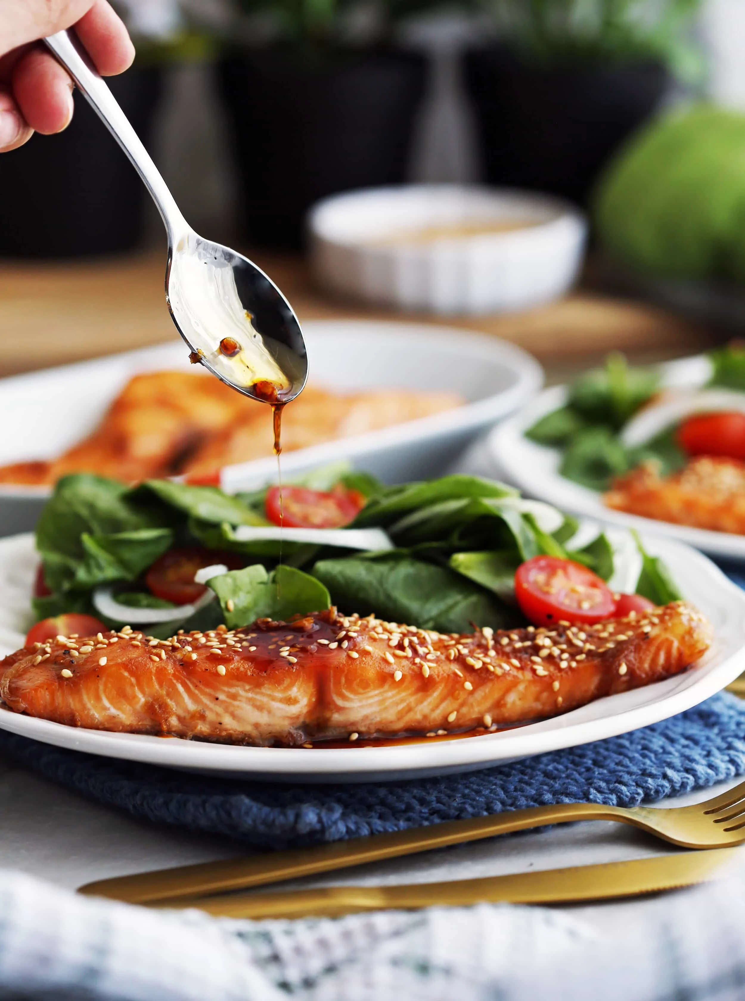 Maple-soy baked salmon on a white plate topped with a spoonful of maple-soy sauce.