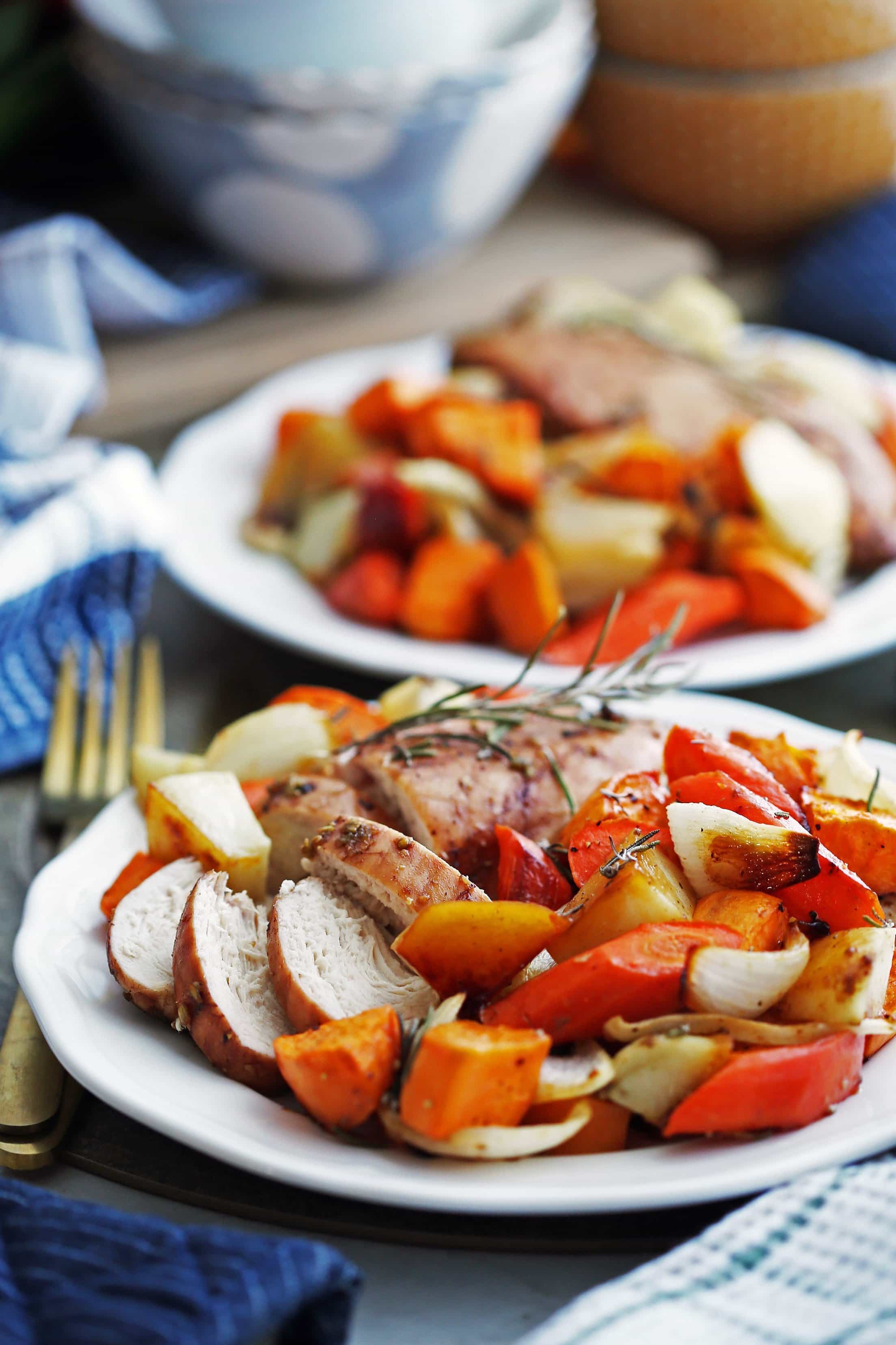 Sheet pan balsamic chicken, roasted carrots, potatoes, sweet potatoes, and onions on two white plates.