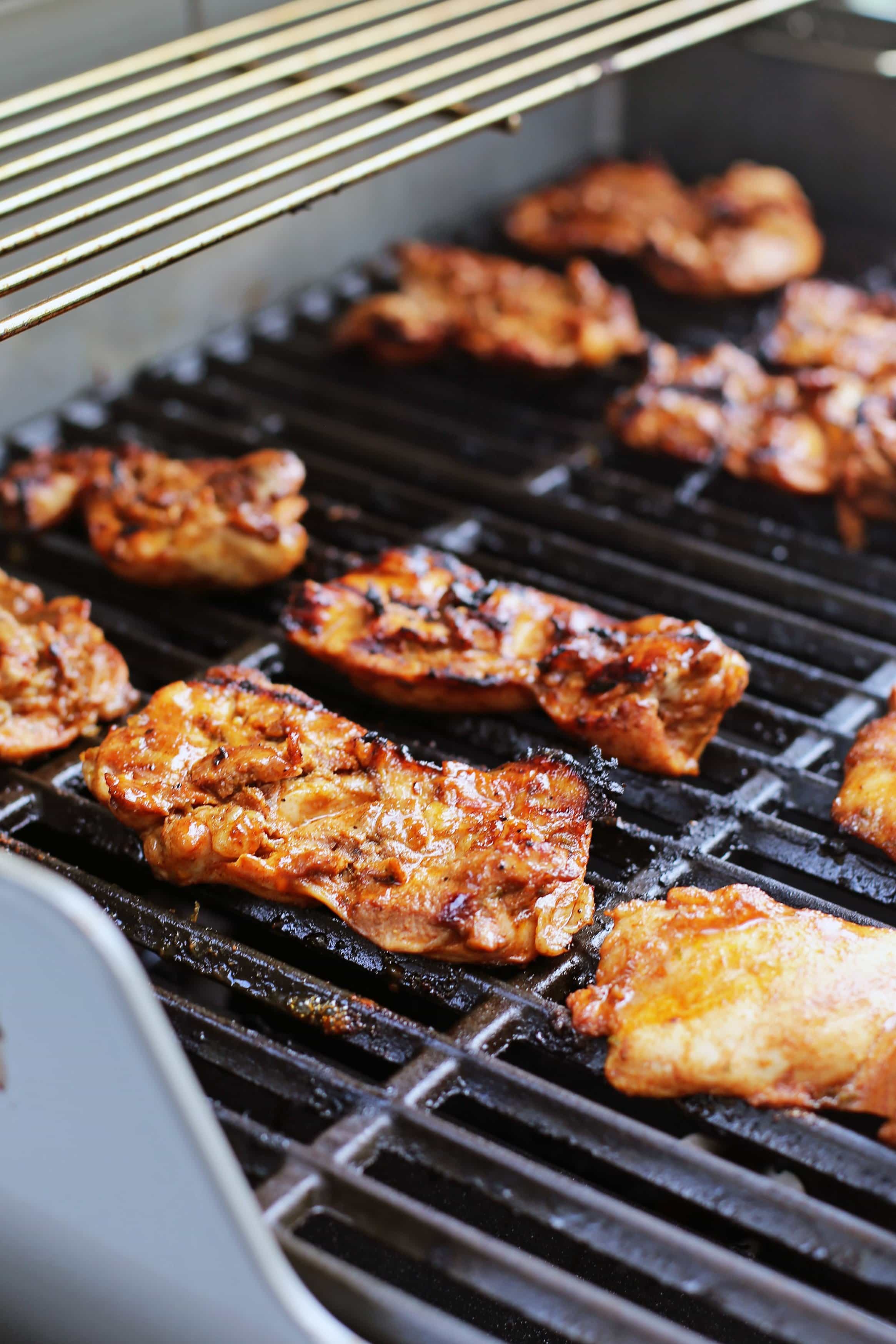 Chili lime chicken thighs cooking on a hot barbecue grill.