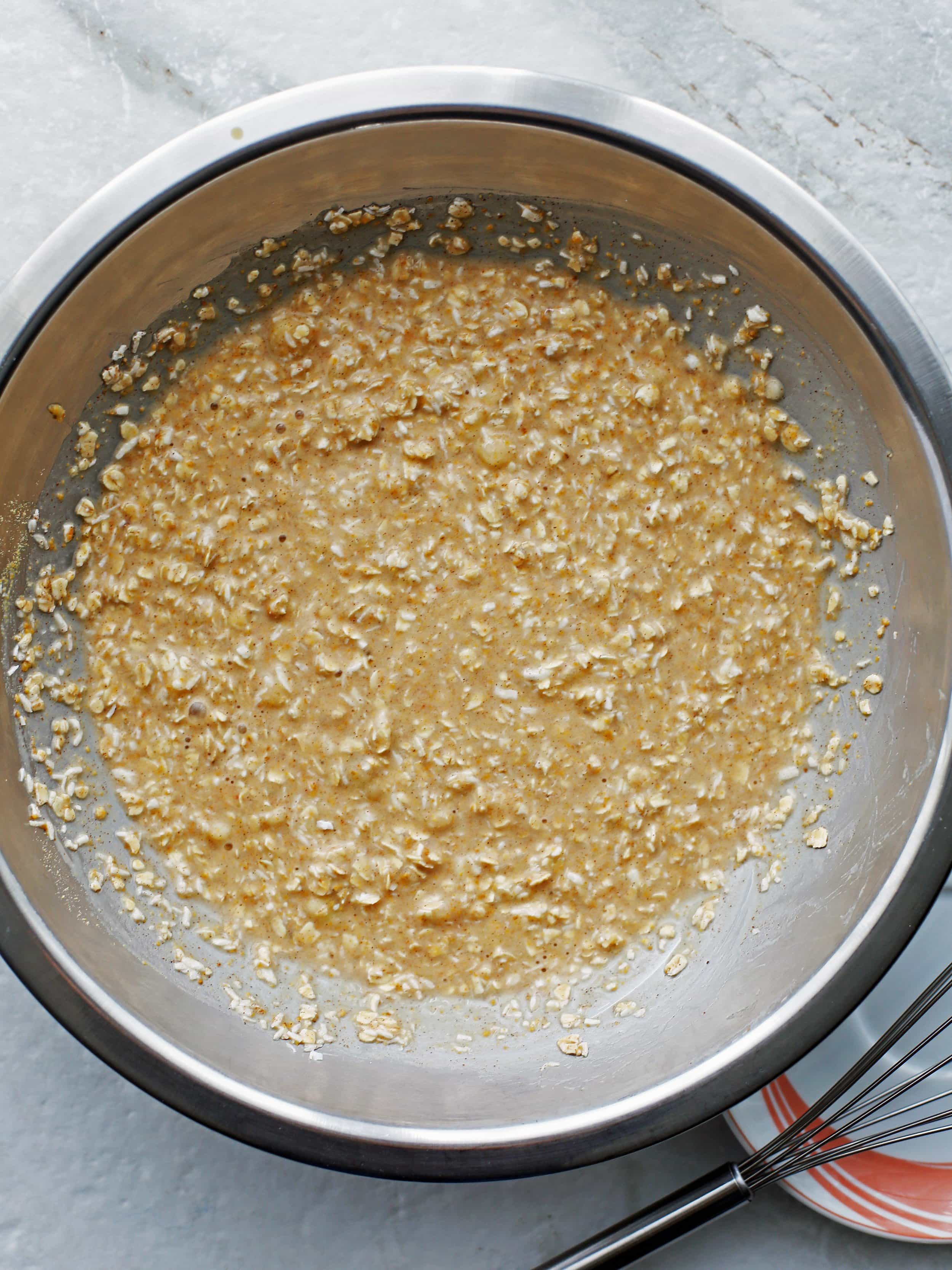 Banana coconut overnight oats ingredients whisked together in a metal bowl.