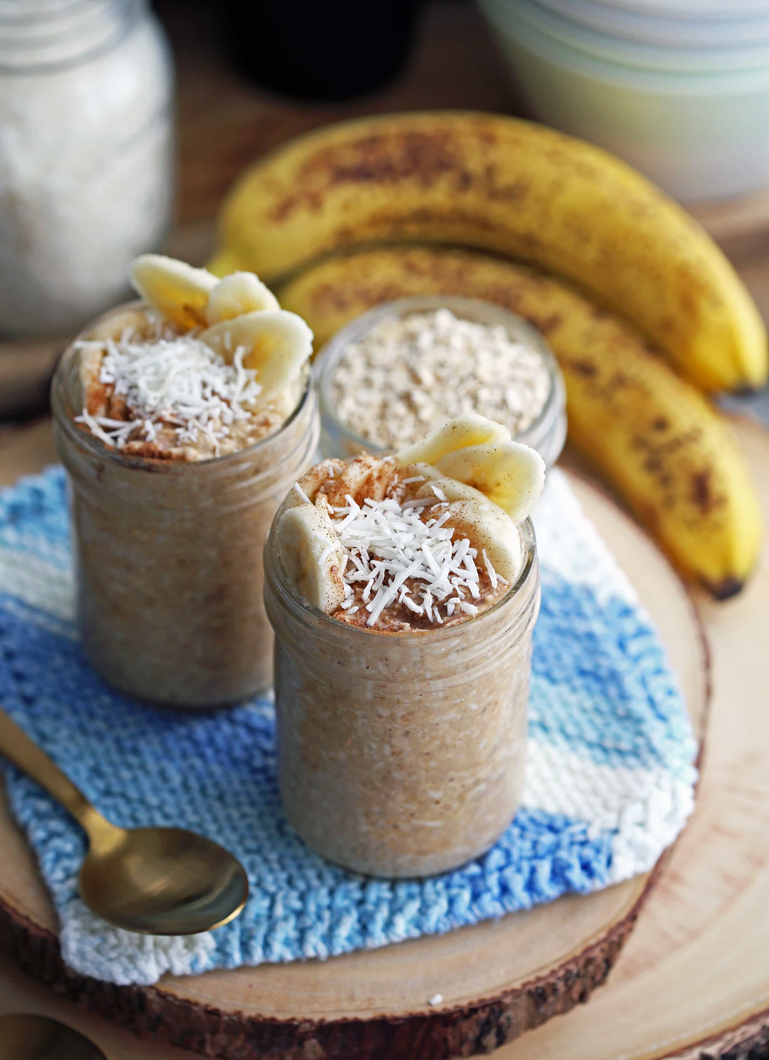 Banana Coconut Cream Pie Overnight Oats topped with bananas, cinnamon, and coconut in two mason jars.