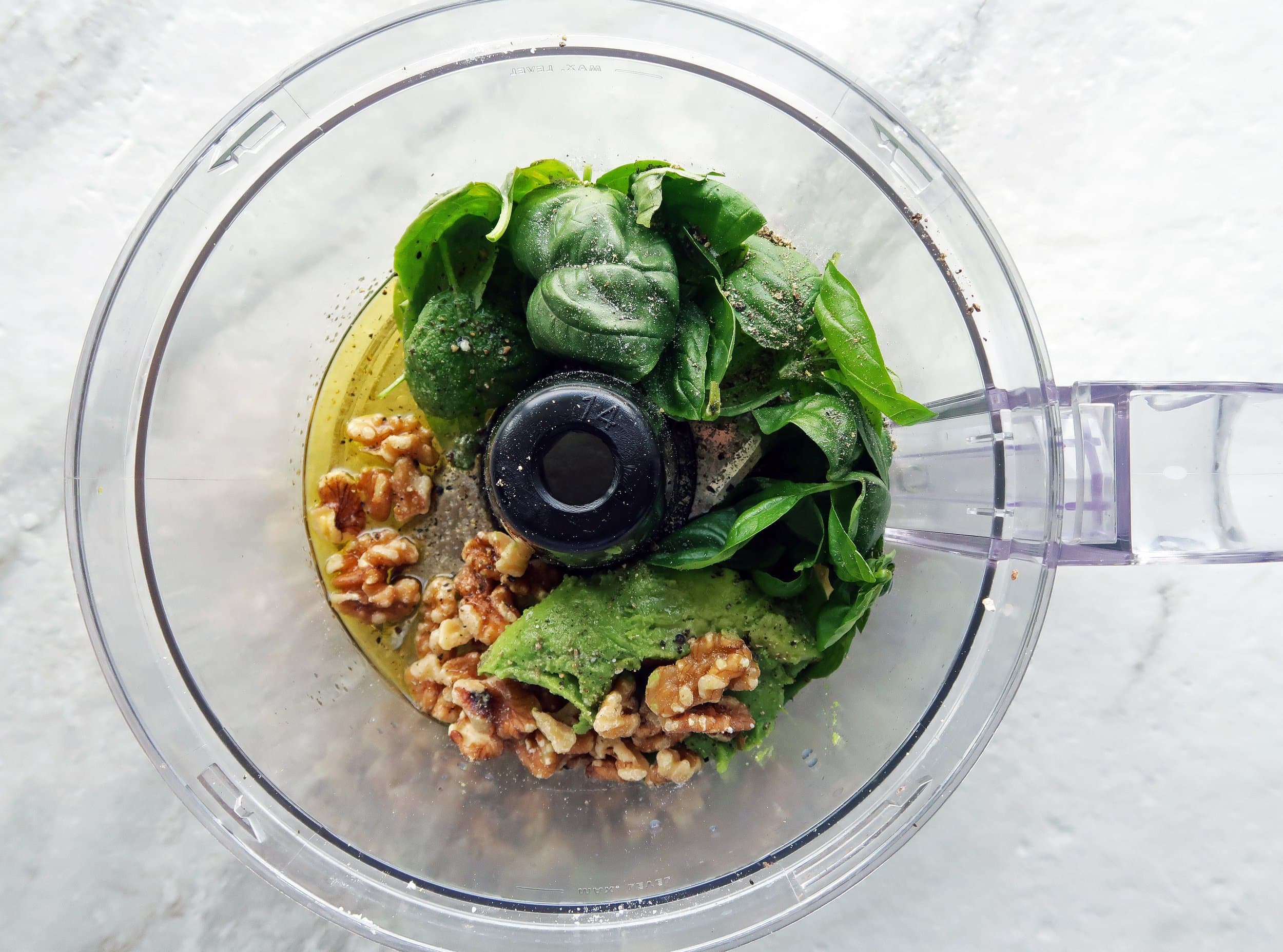 Fresh basil, avocado, walnuts, olive oil, salt, and pepper in a food processor.