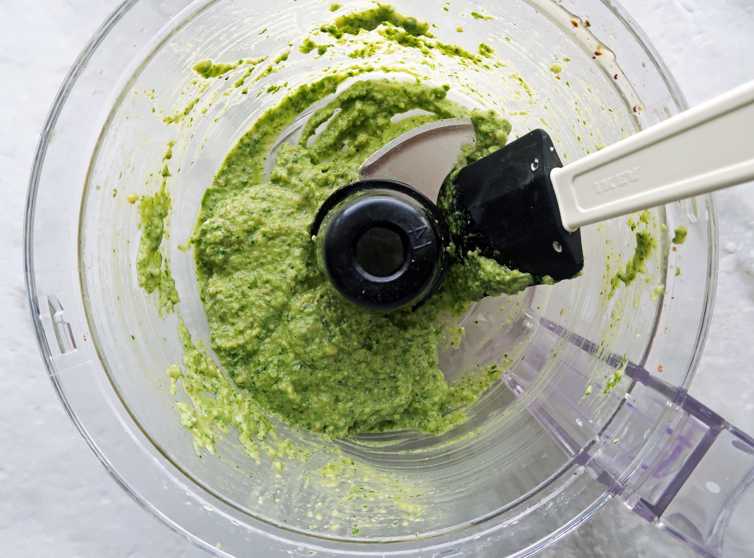 Creamy fresh basil avocado pesto in a food processor.