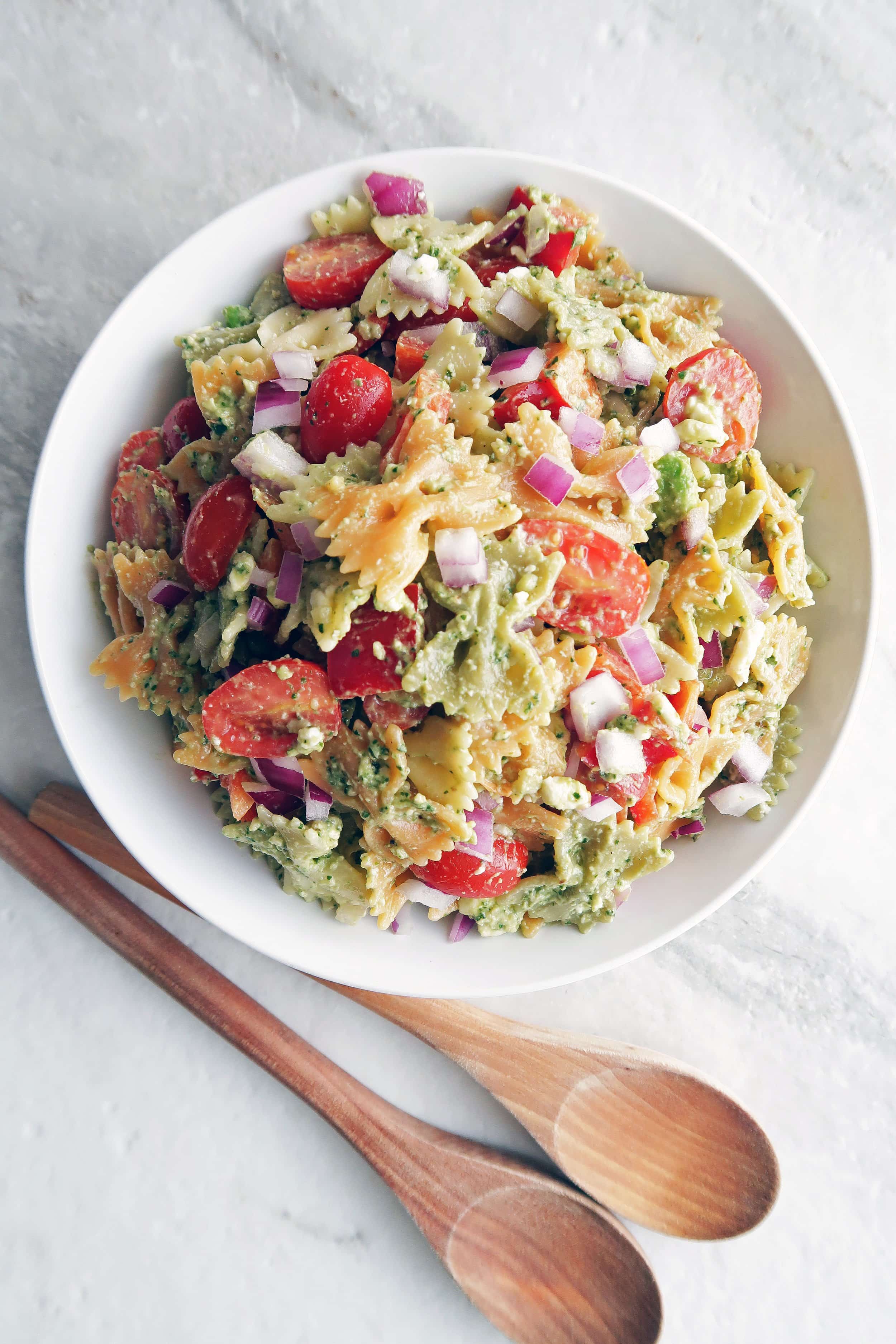 Overhead view of Basil avocado pesto vegetable pasta salad in a large white bowl.