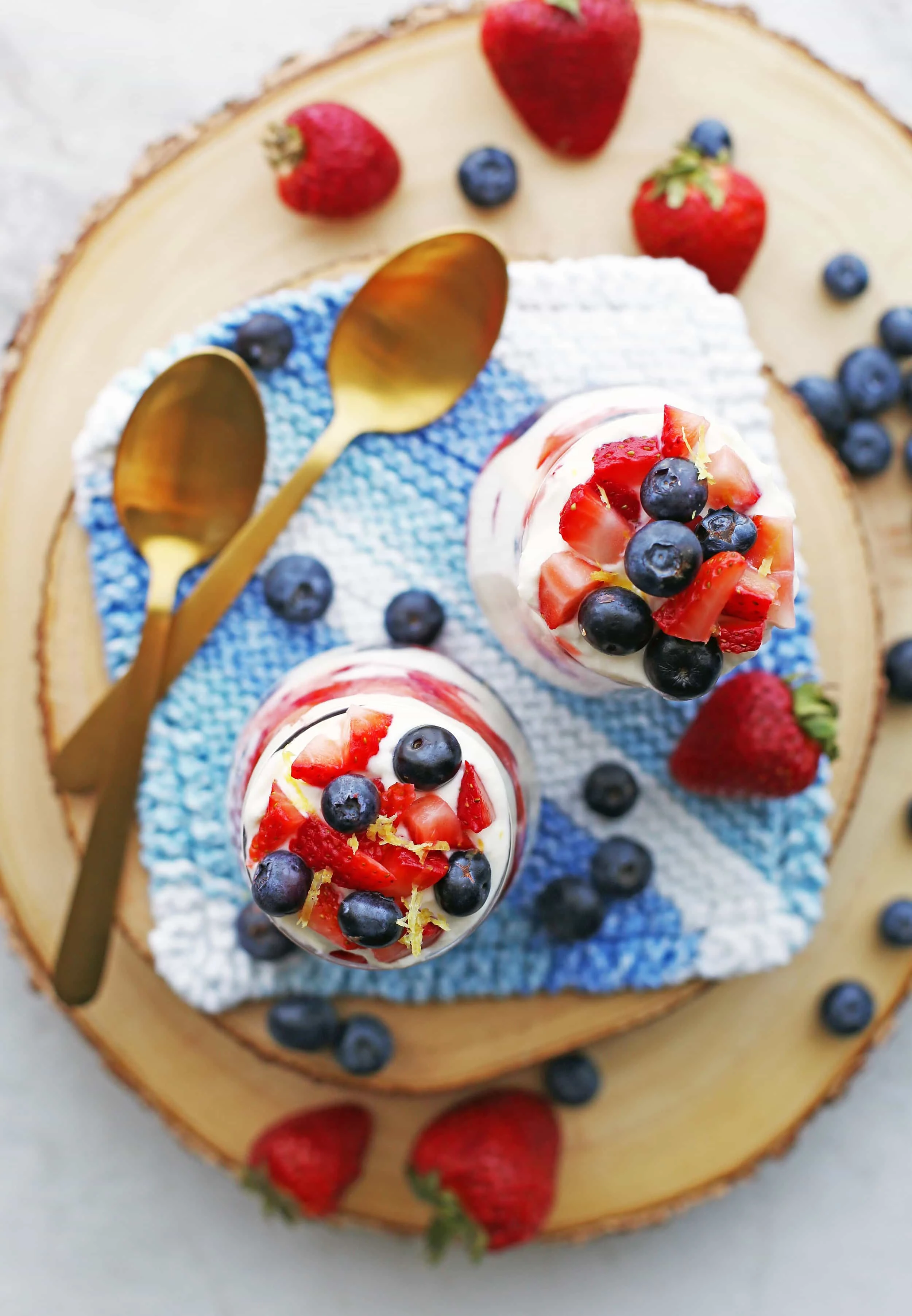 Overhead view of two glasses full of fresh strawberries, blueberries, and honey lemon mascarpone cream.