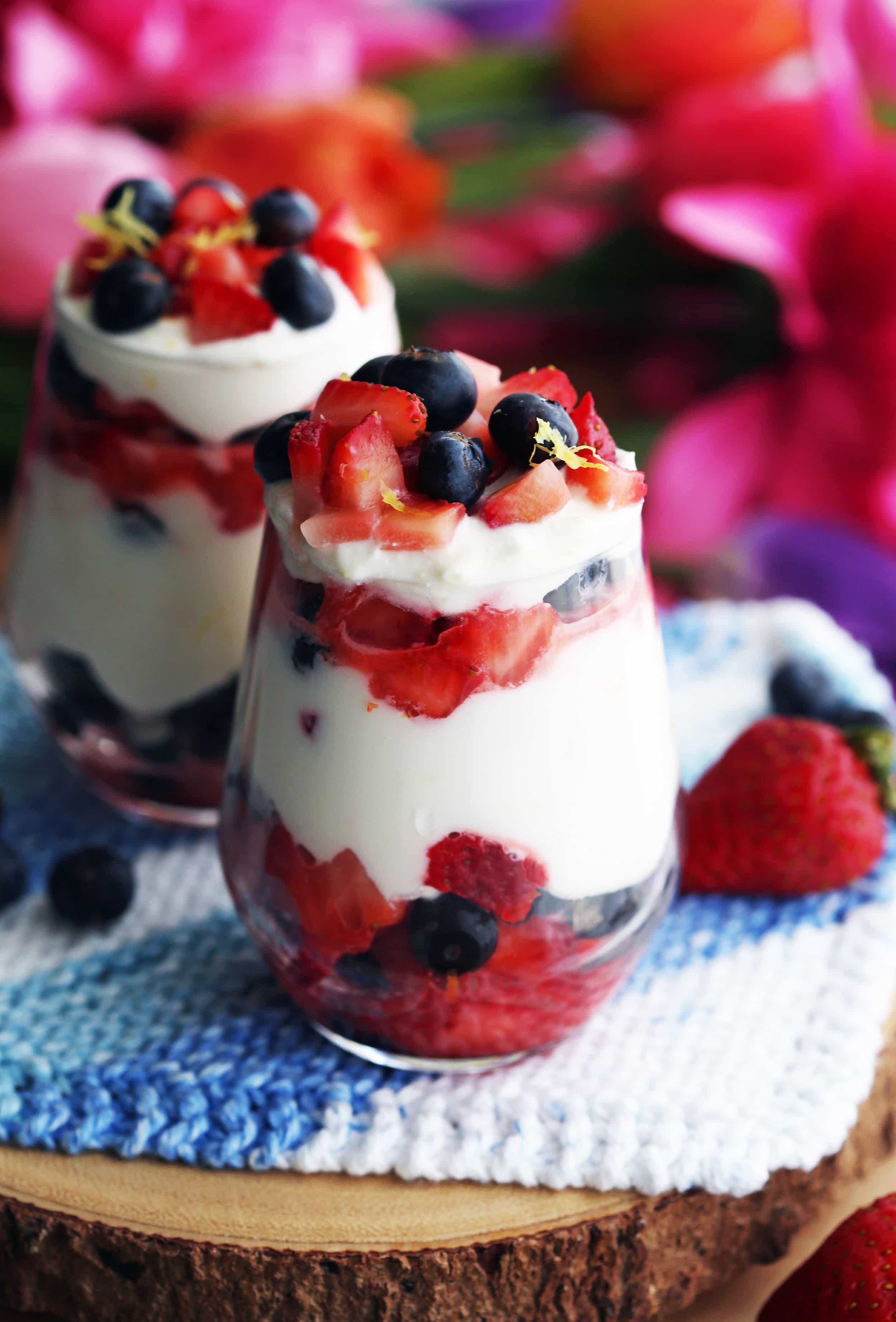 Closeup of fresh strawberries, blueberries, and honey lemon mascarpone cream layered in two glasses.