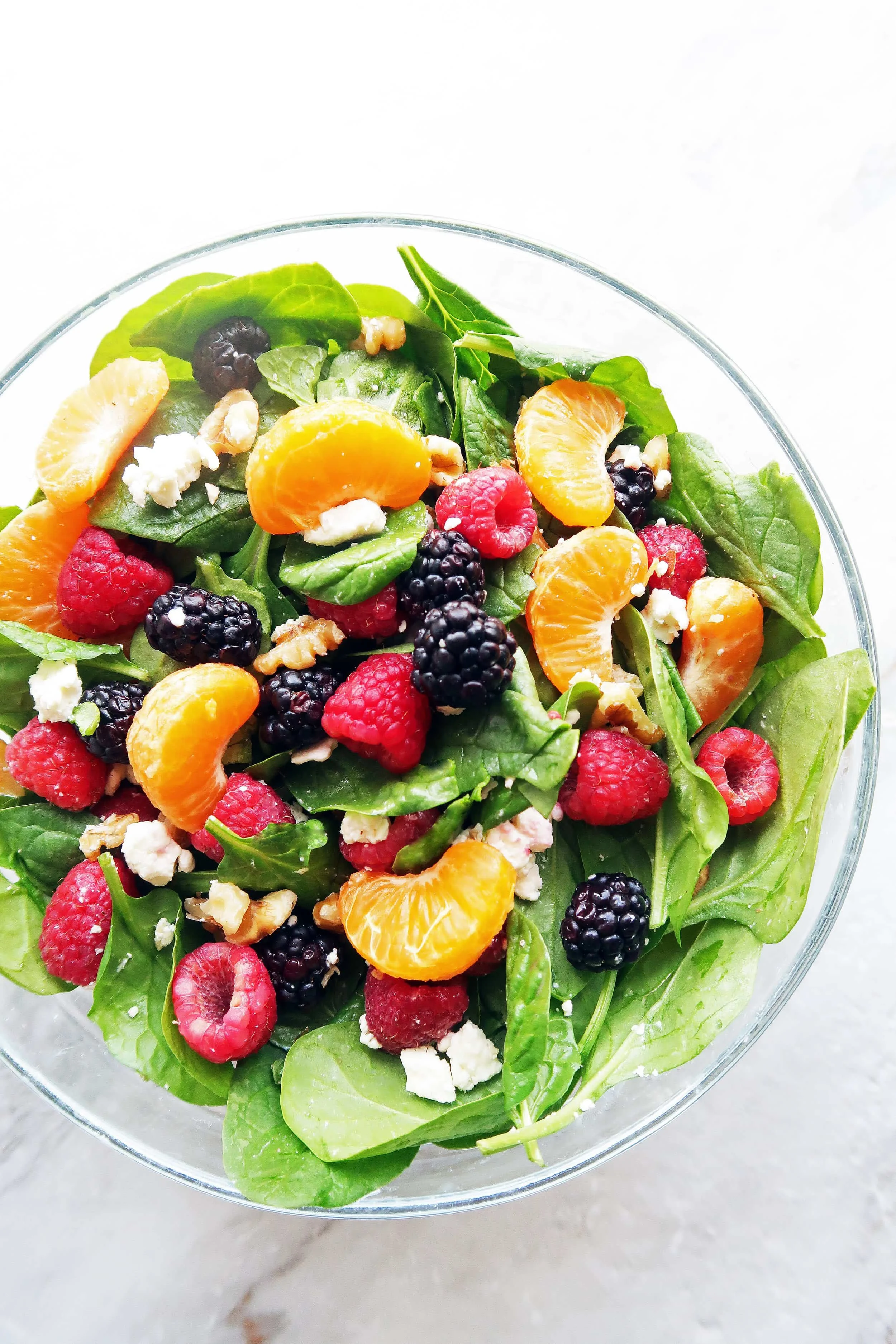 Berry Orange Spinach Salad mixed in a large bowl, which includes raspberries, blackberries, and mandarin oranges.