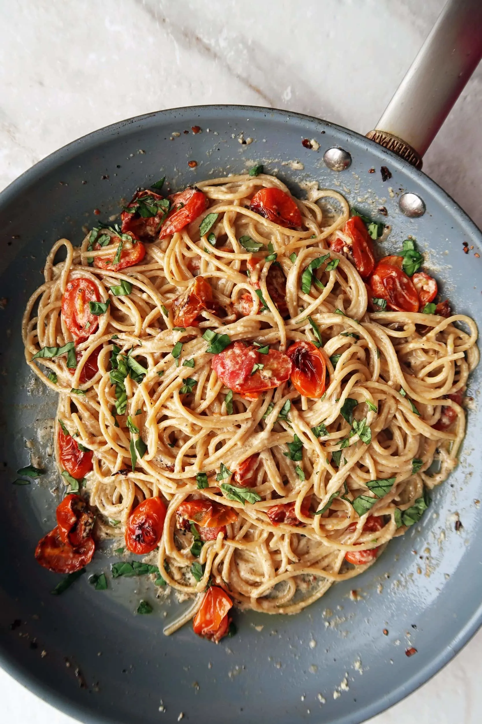 Black pepper and parmesan spaghetti (cheese and pepper pasta) with garlic roasted tomatoes tossed in a skillet.