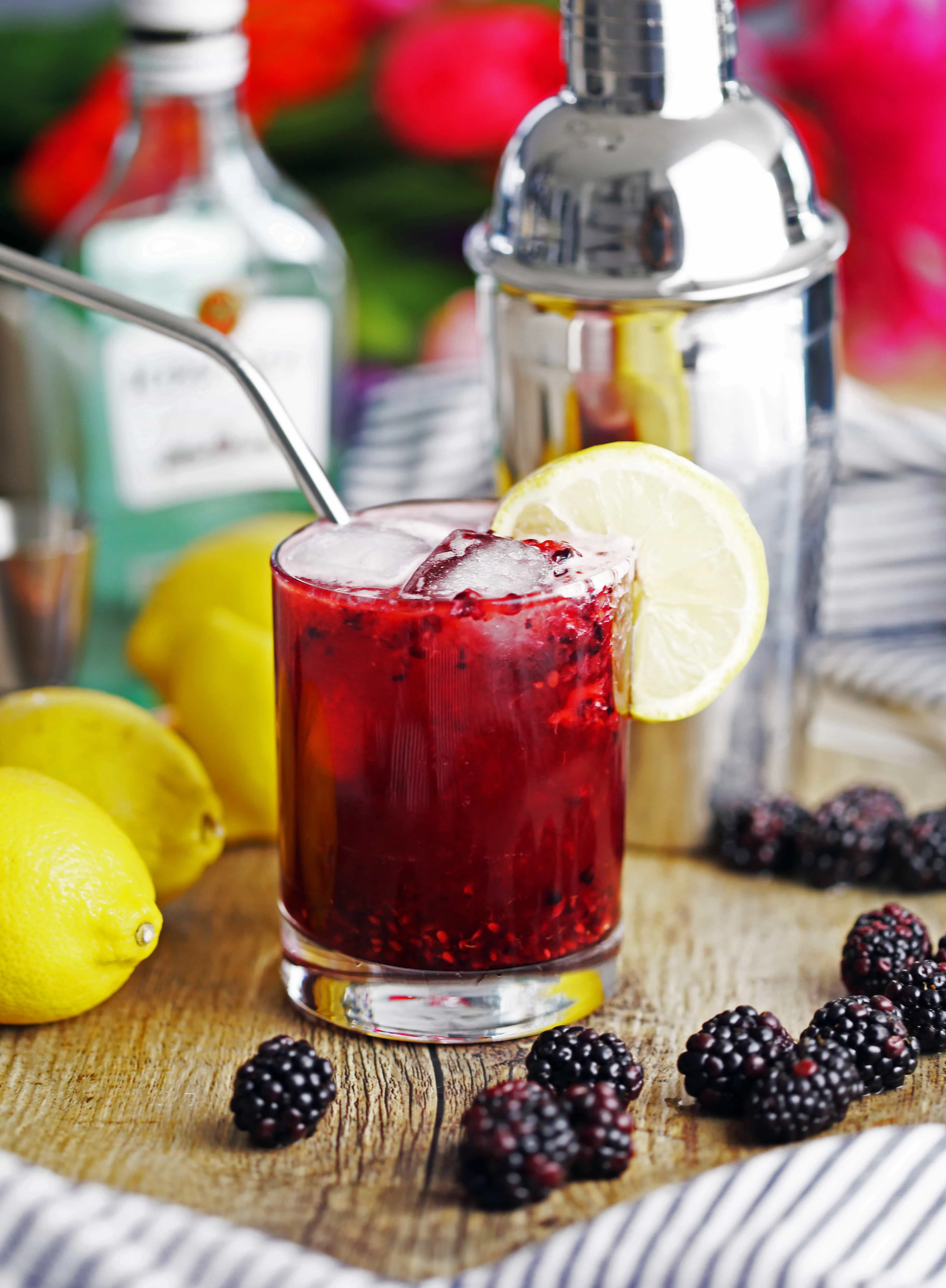 Blackberry Lemon Smash drink in a glass surrounded by fresh blackberries and lemons.