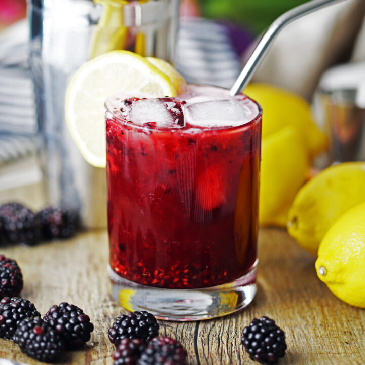 Blackberry lemon smash made with gin in a double old-fashioned glass with a lemon slice.