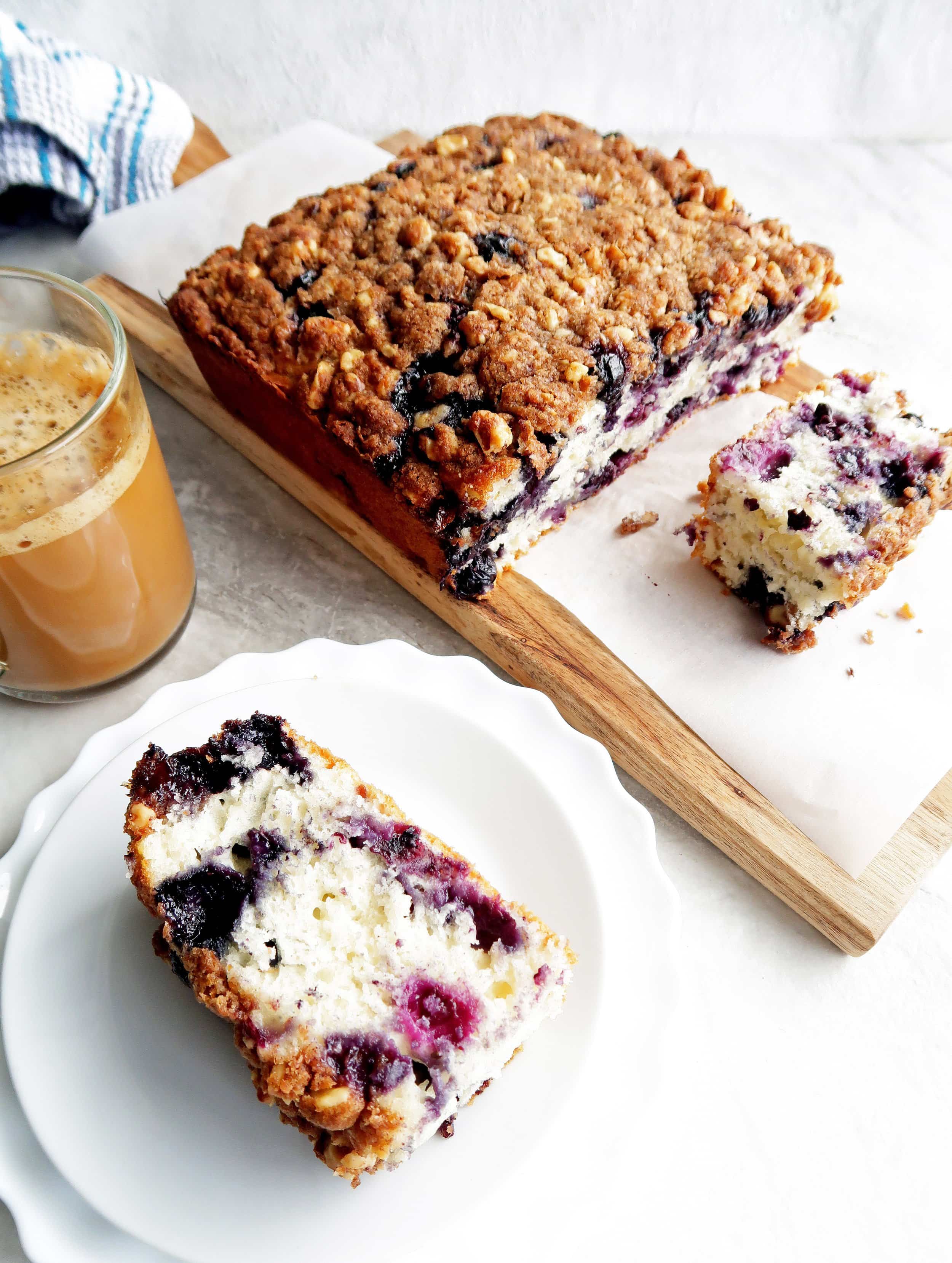 A slice blueberry coffee cake with brown sugar crumble on a white plate.