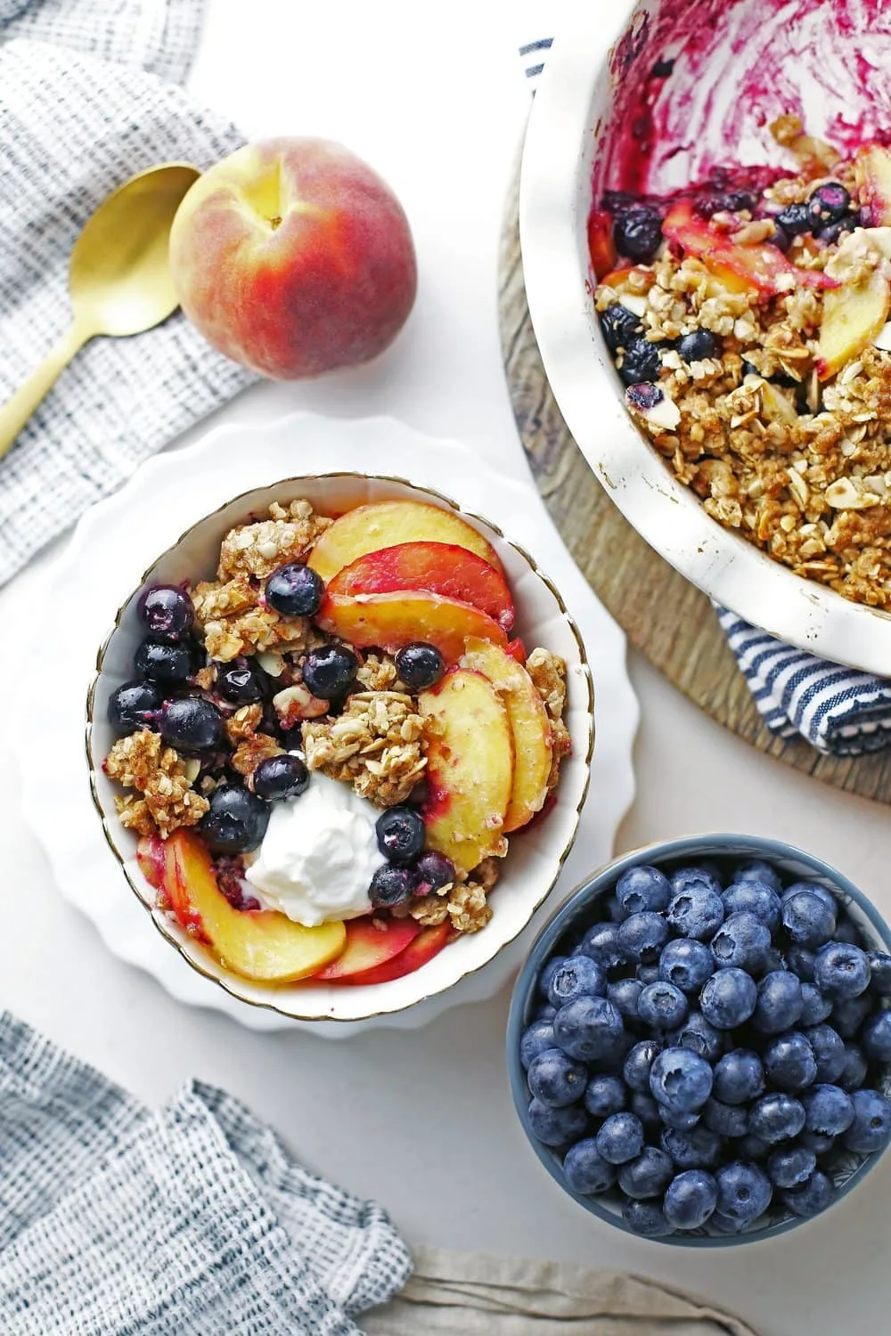 Overhead view of a bowl of blueberry peach crisp with more on the side.