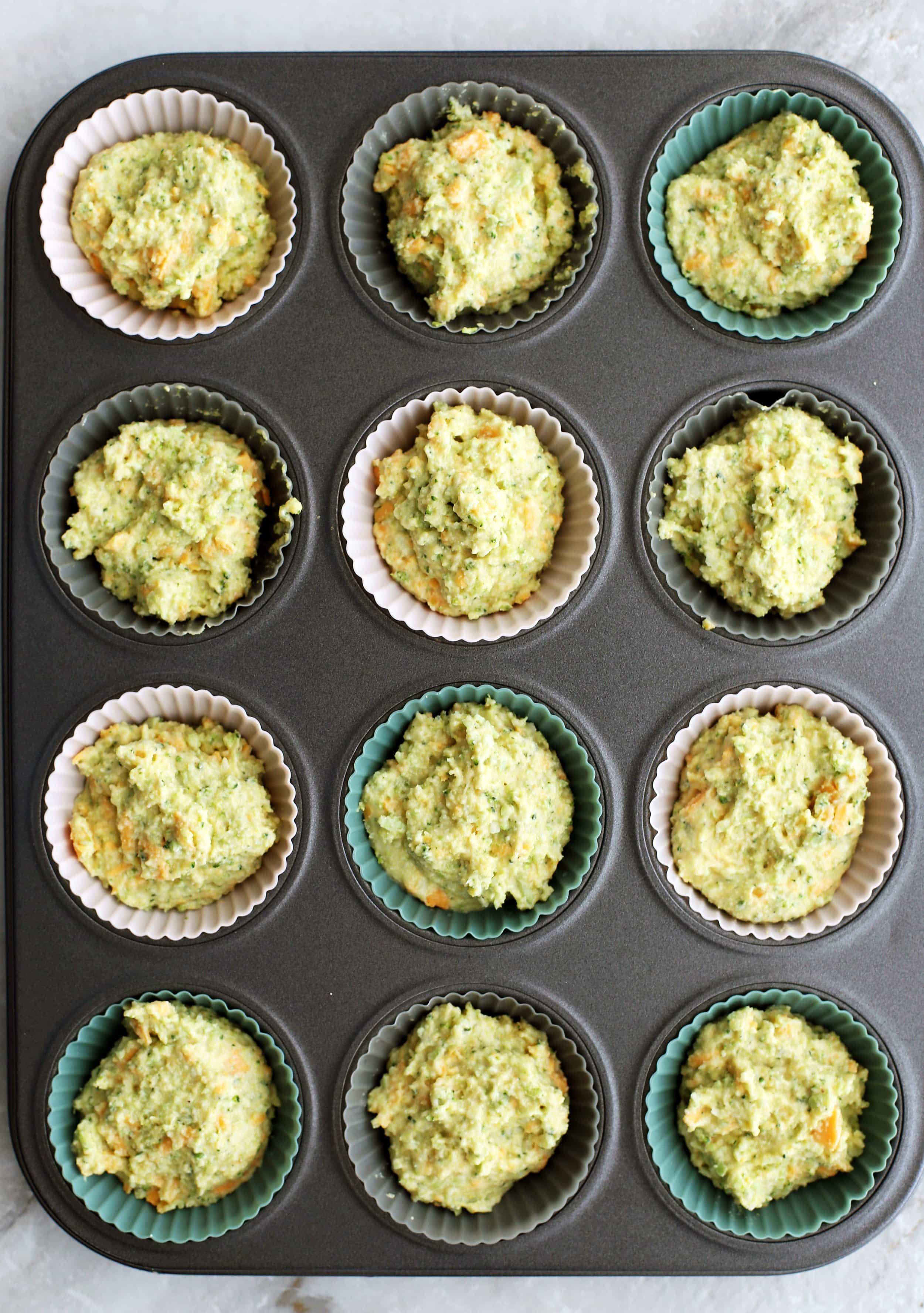 Broccoli Cheddar Cornbread Muffin batter scooped into a muffin pan.