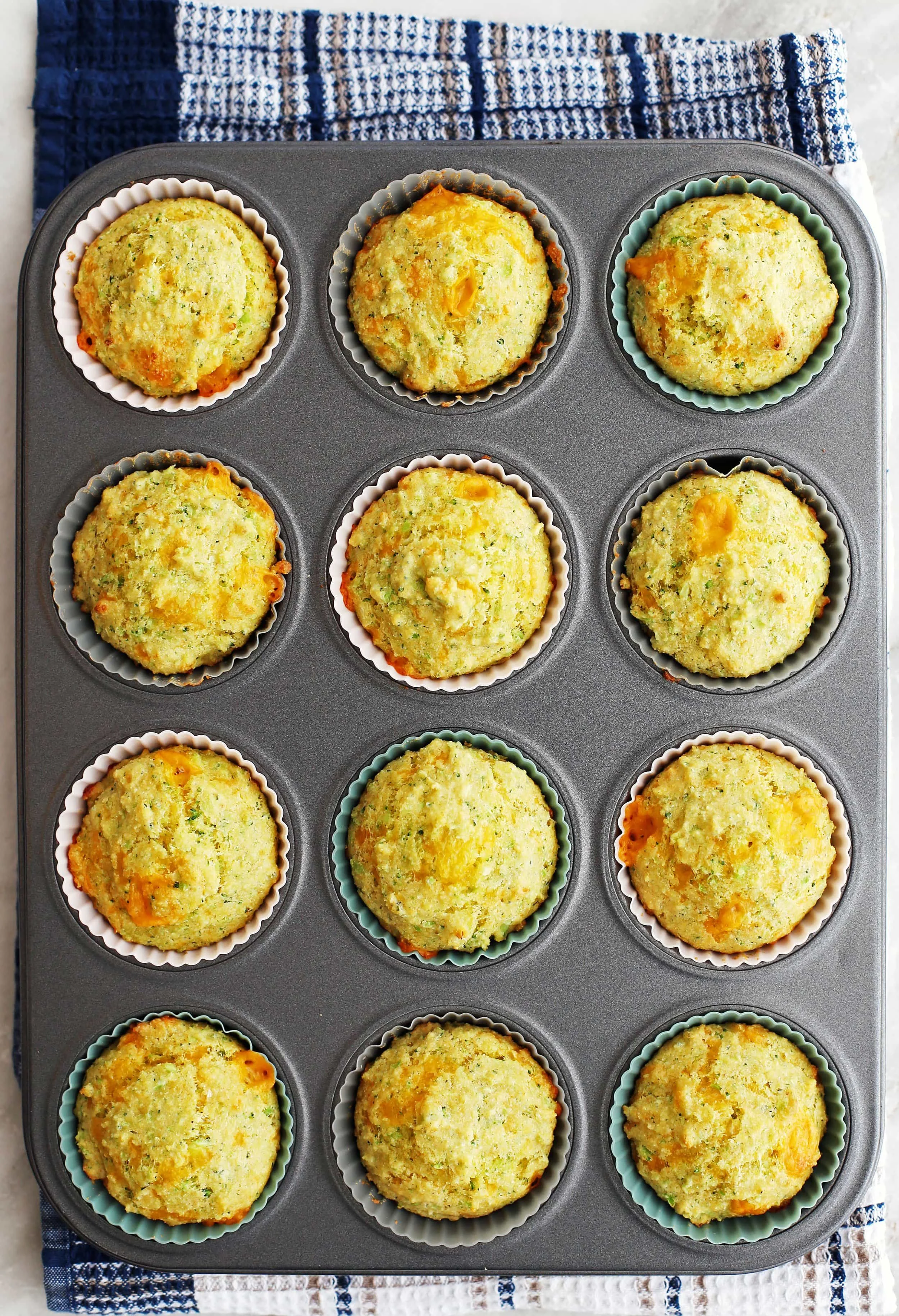 Twelve Broccoli Cheddar Cornbread Muffins in a muffin pan.