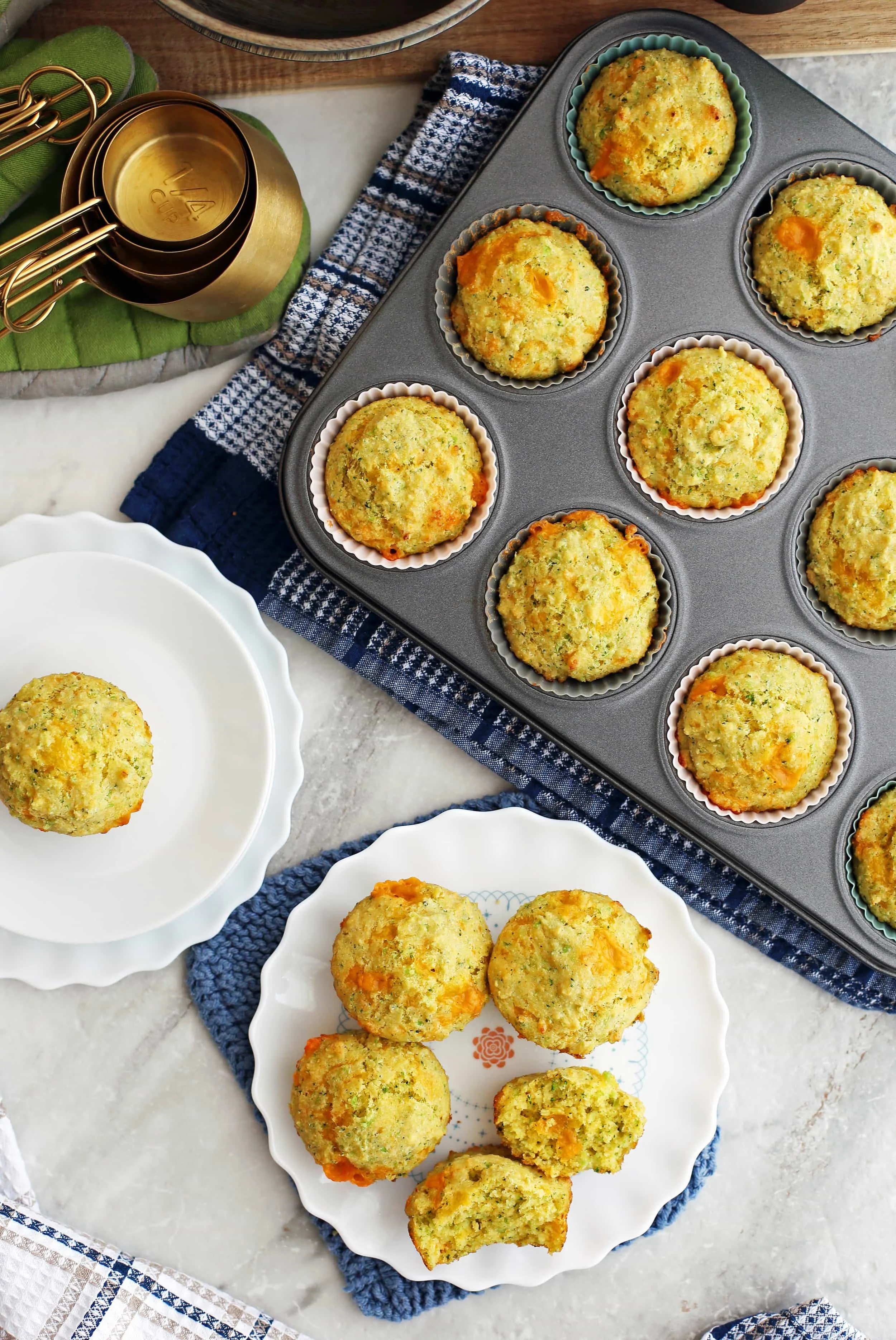Overhead view of Broccoli Cheddar Cornbread Muffins on two white plates and a muffin pan.