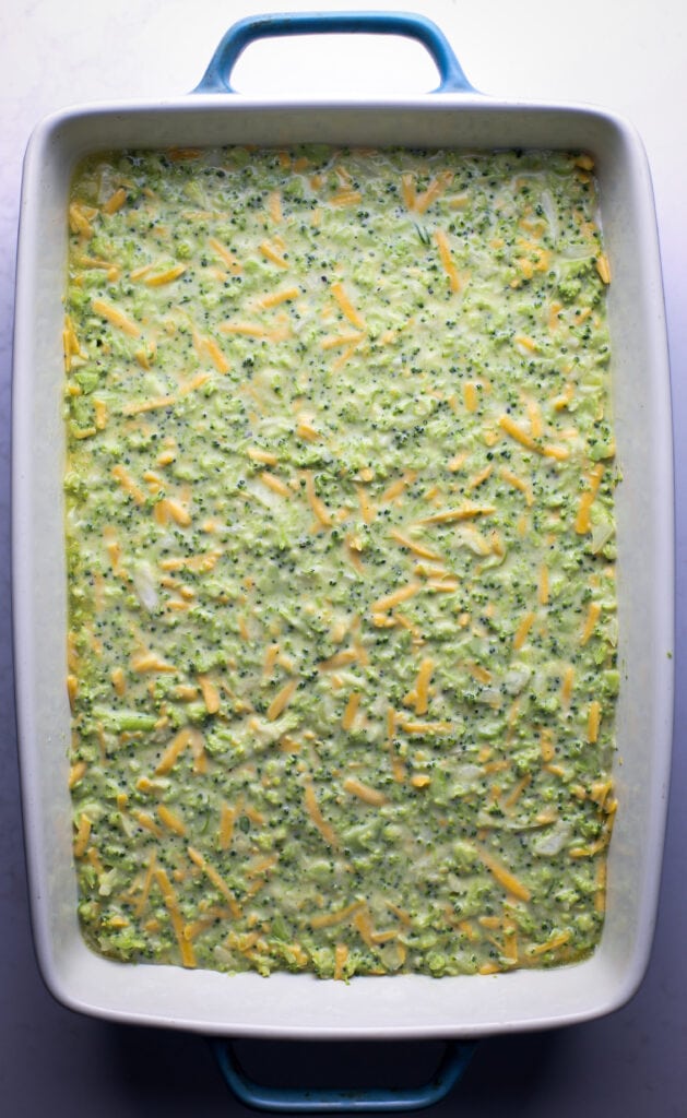 Unbaked Broccoli cheddar squares batter in a rectangular baking dish.