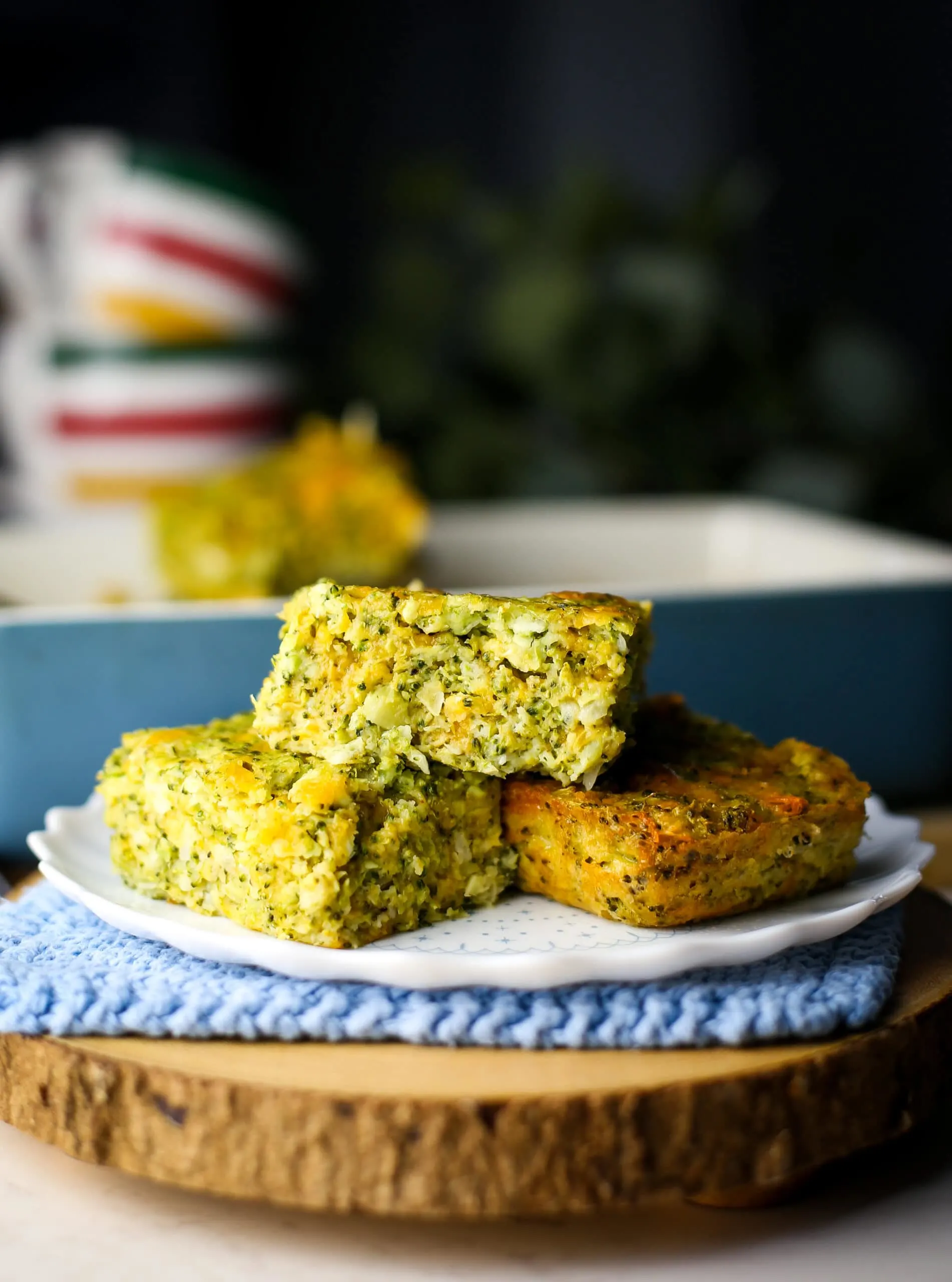 Three broccoli cheddar squares piled on a white plate.